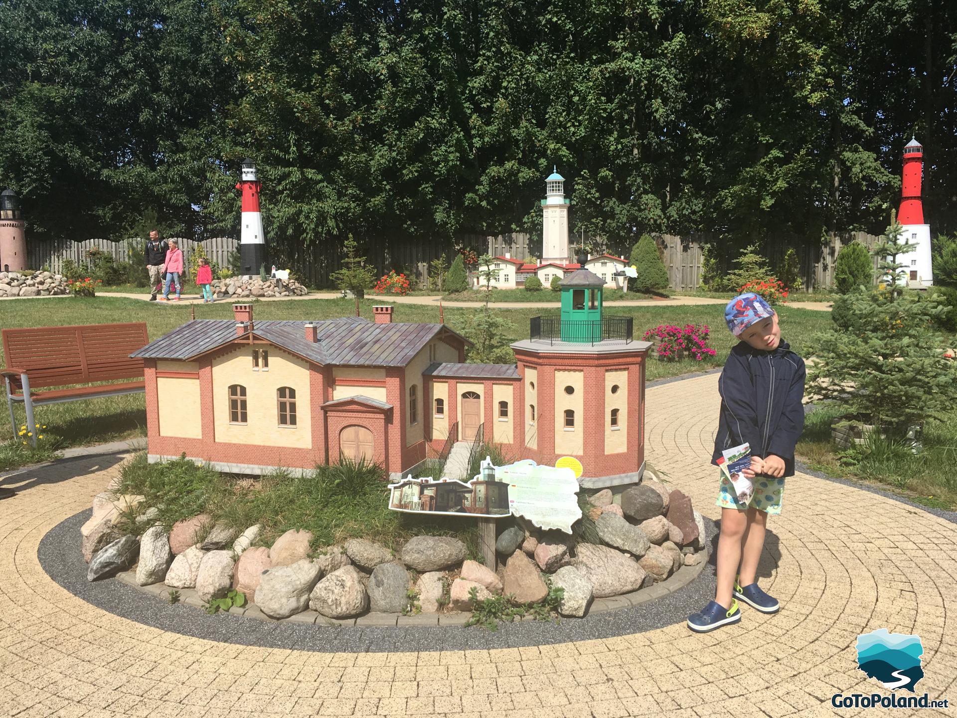 a boy is in the miniature park, he is standing near the miniature lantern 