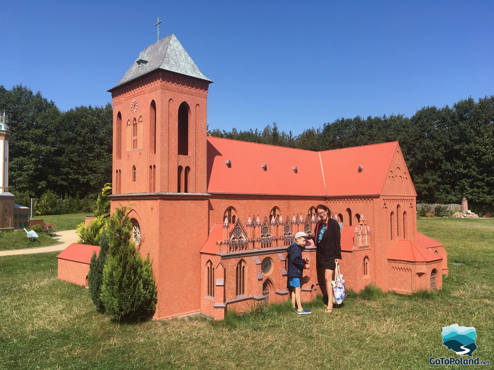 a boy and a woman standing by the church in the miniature park