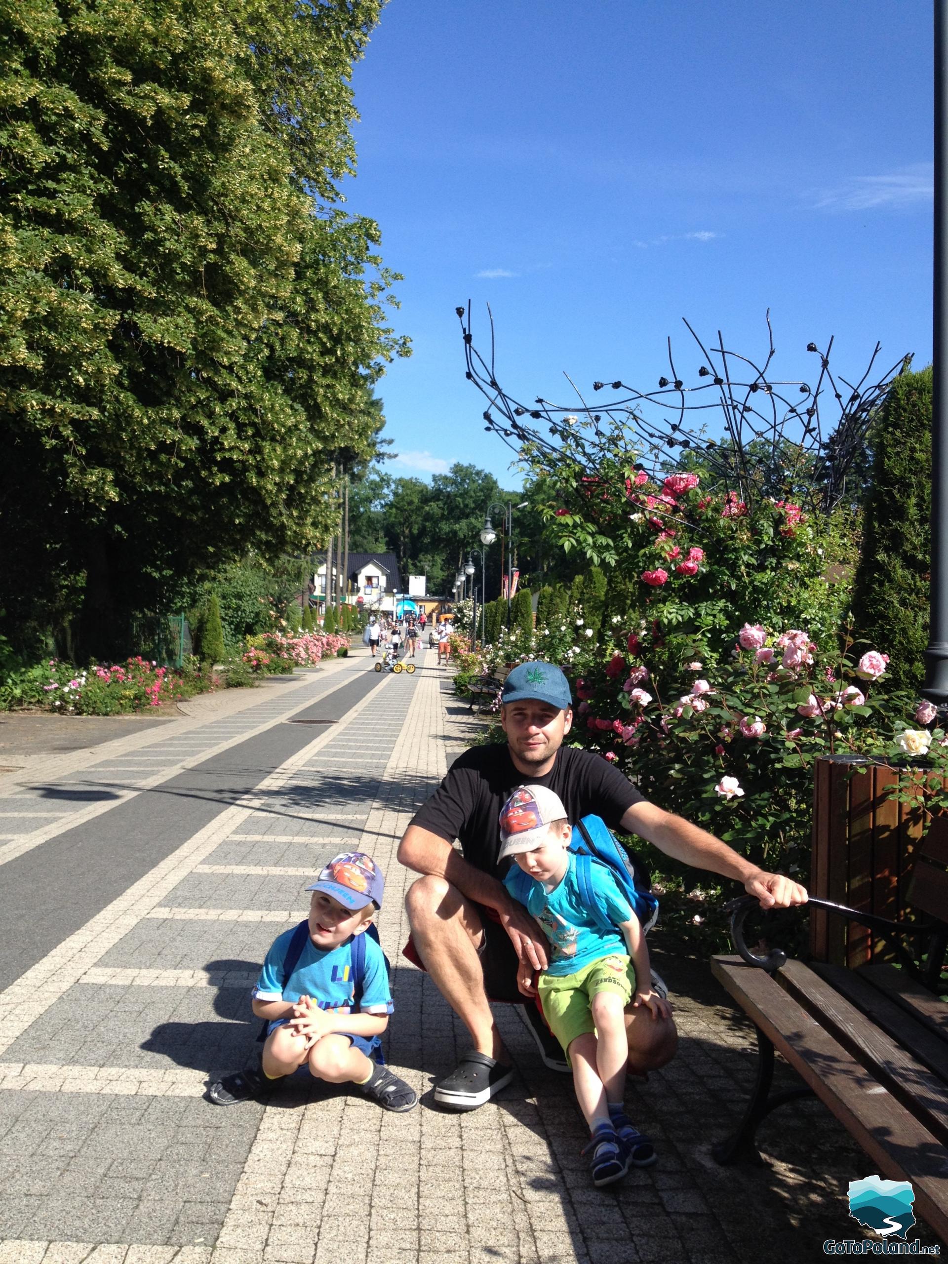 a man and two boys on an avenue lined with roses