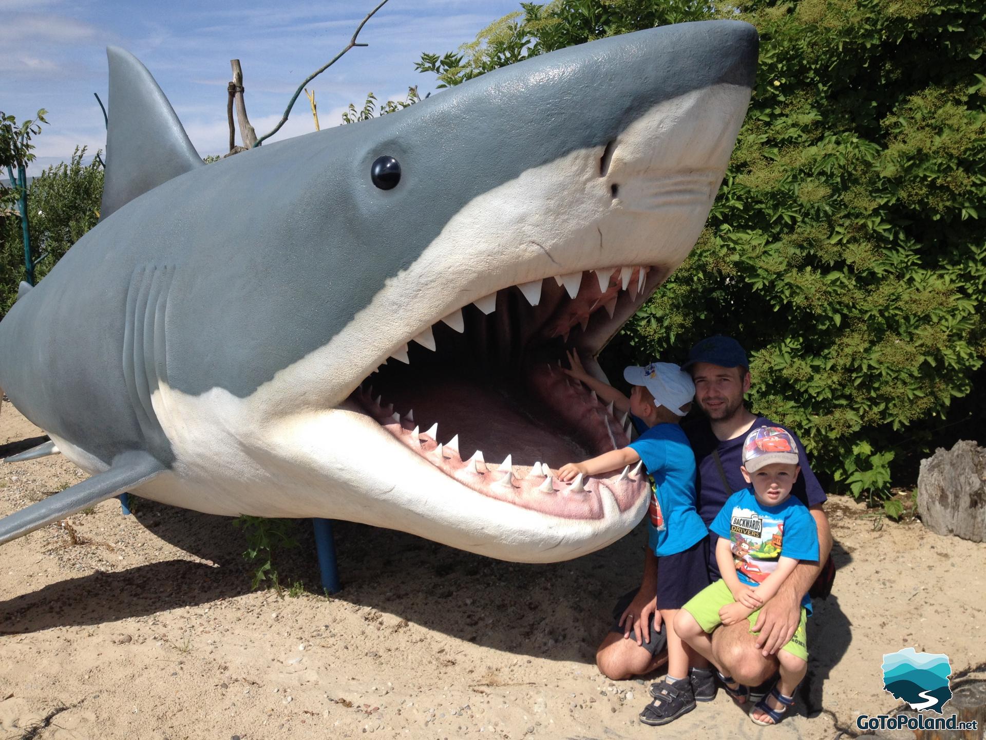 a shark model and two boys and a man next to it