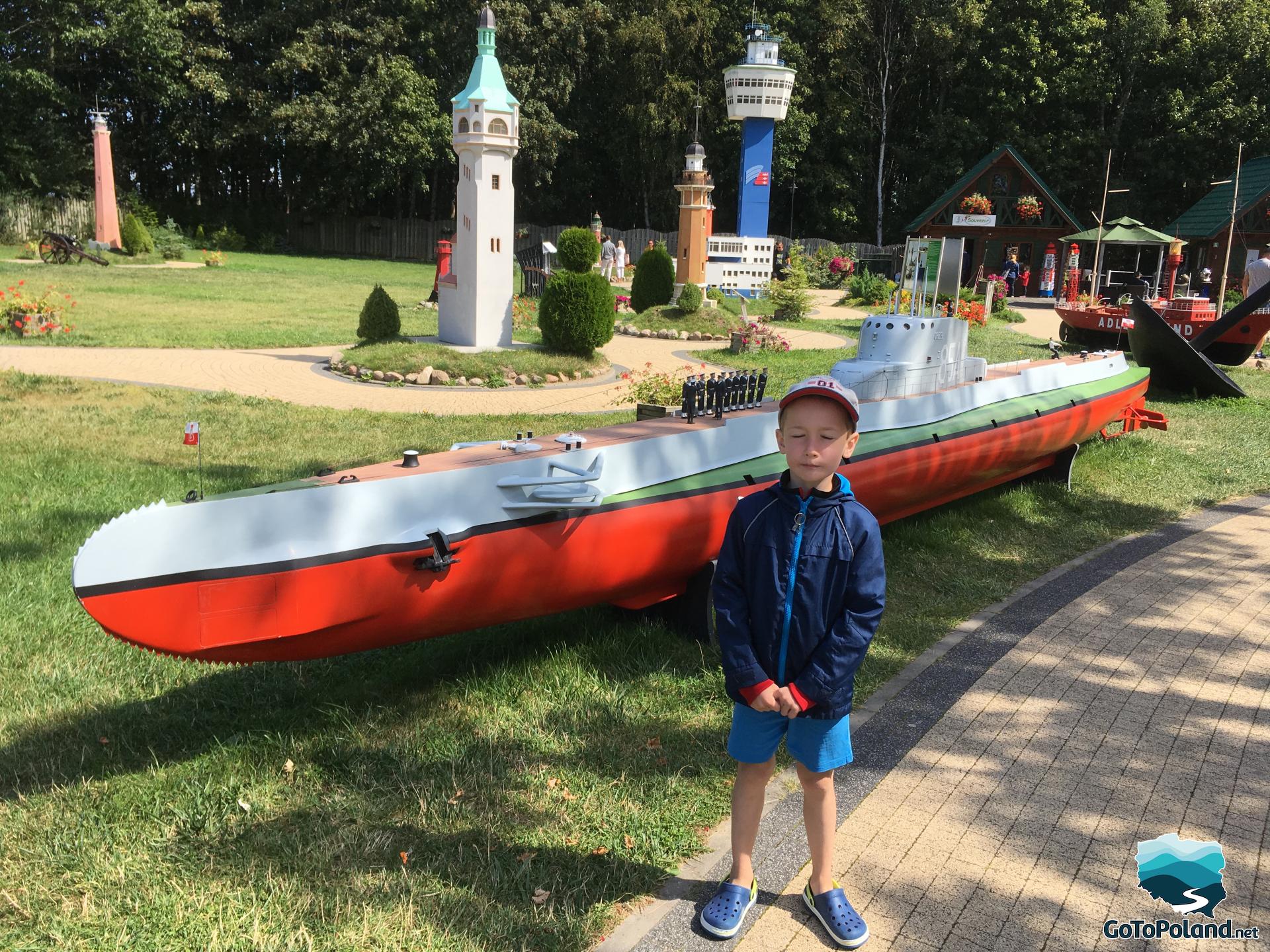 a boy standing by the model of ship