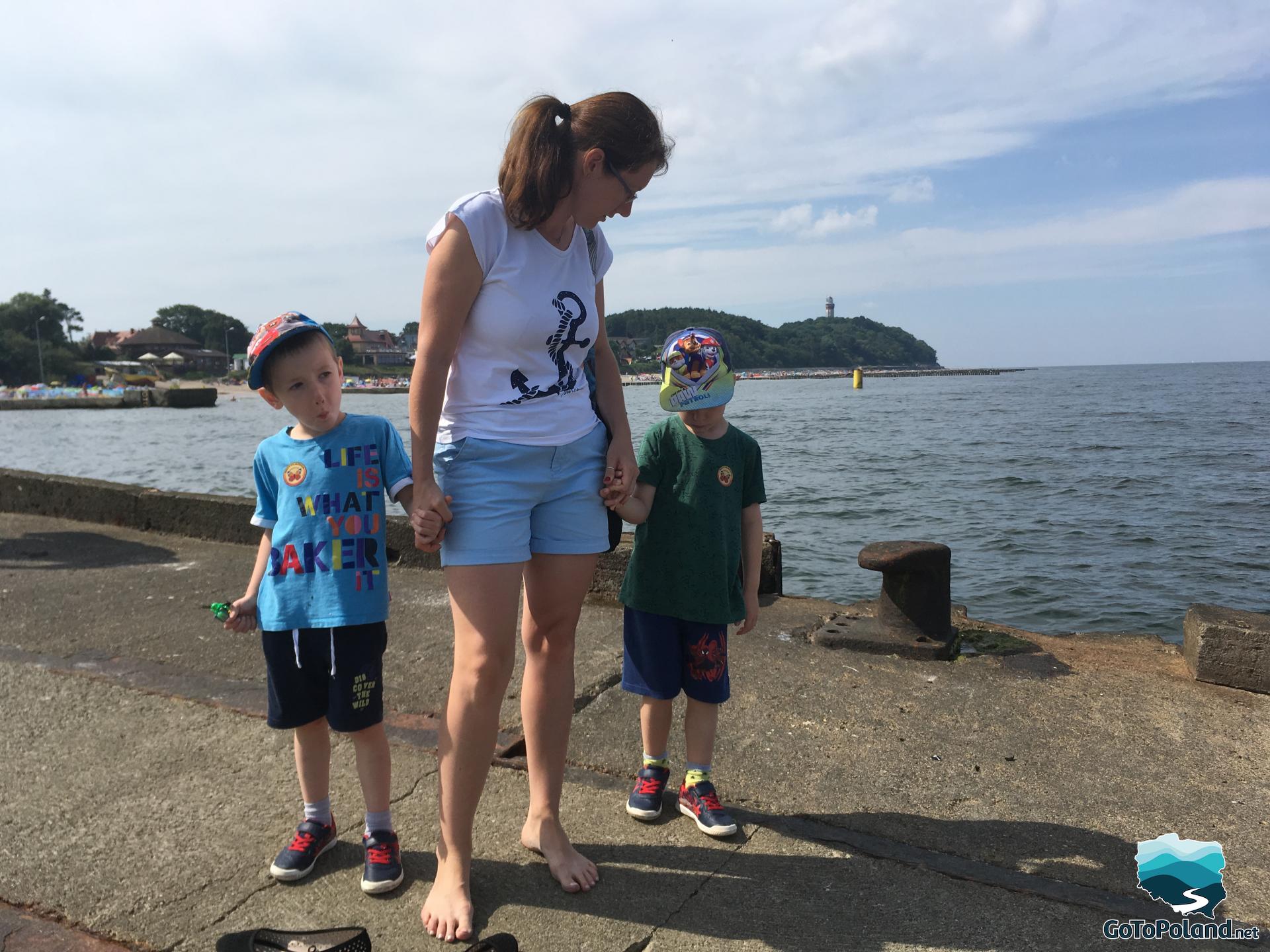 a woman with two children is standing on a concrete pier