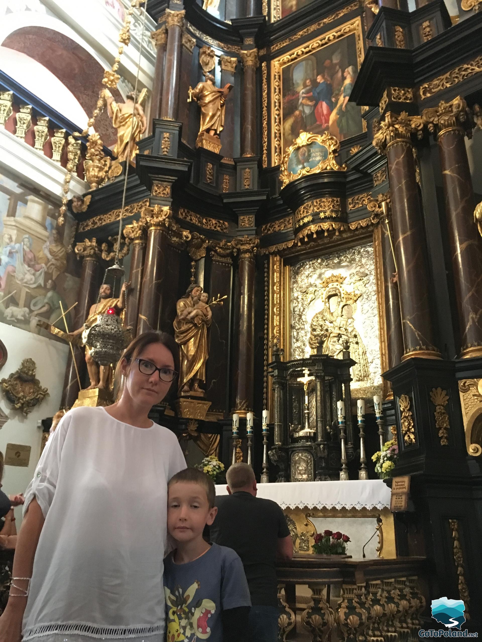 a woman and a boy standing in front of the main altar