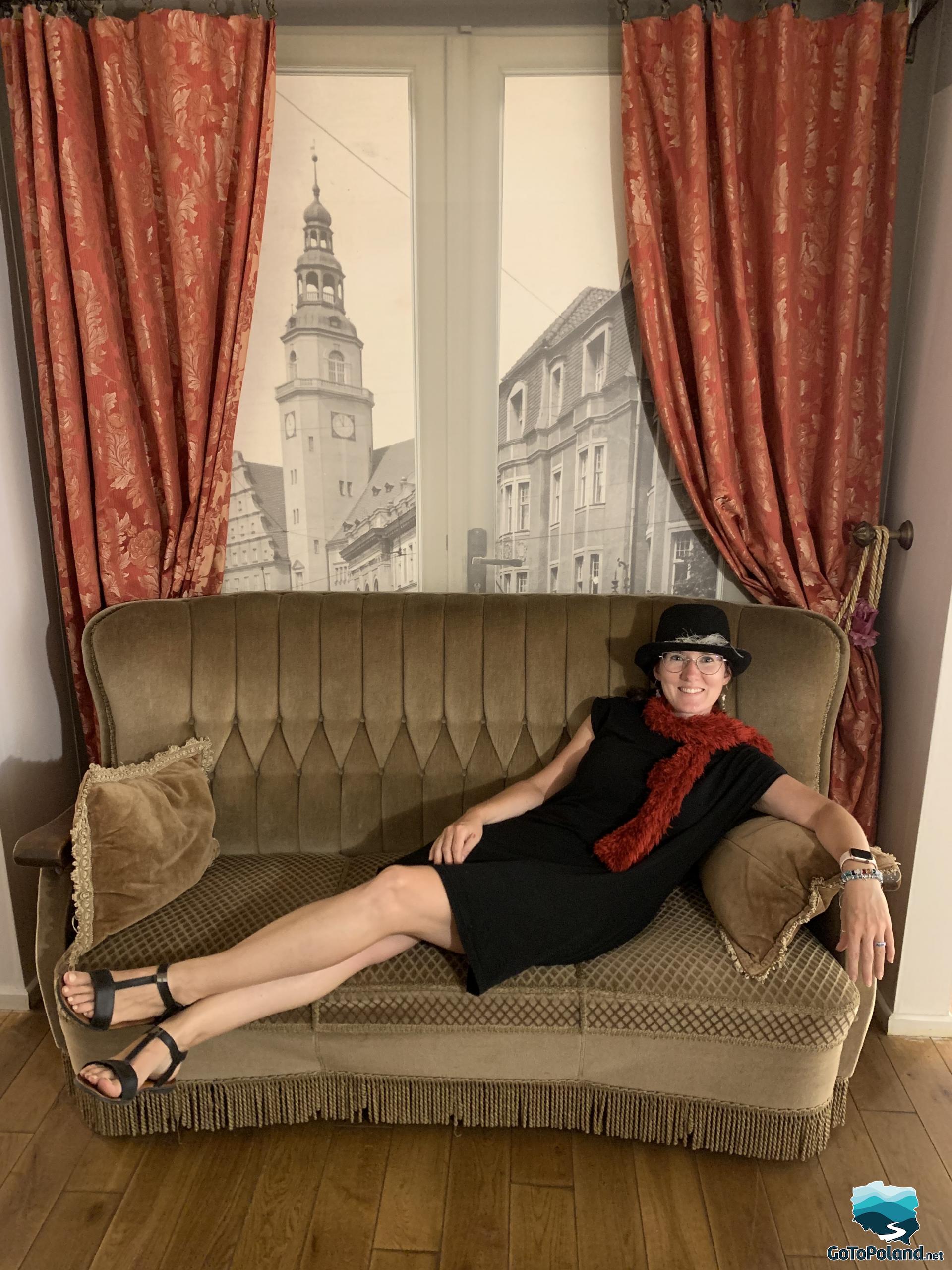 a woman in a hat is lying on the sofa