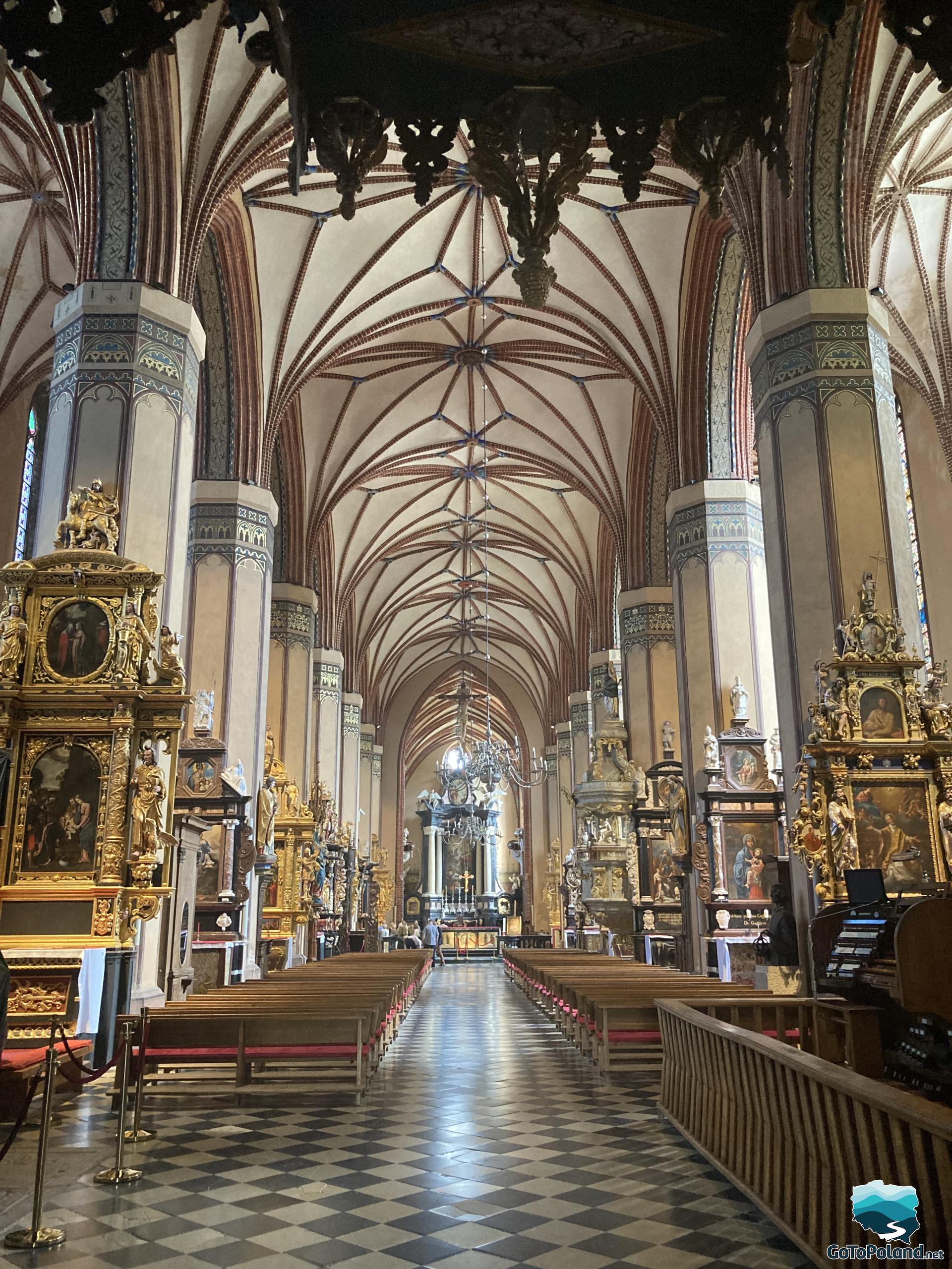 view of the interior of the cathedral, seeing the historic sculptures, the altar, benches