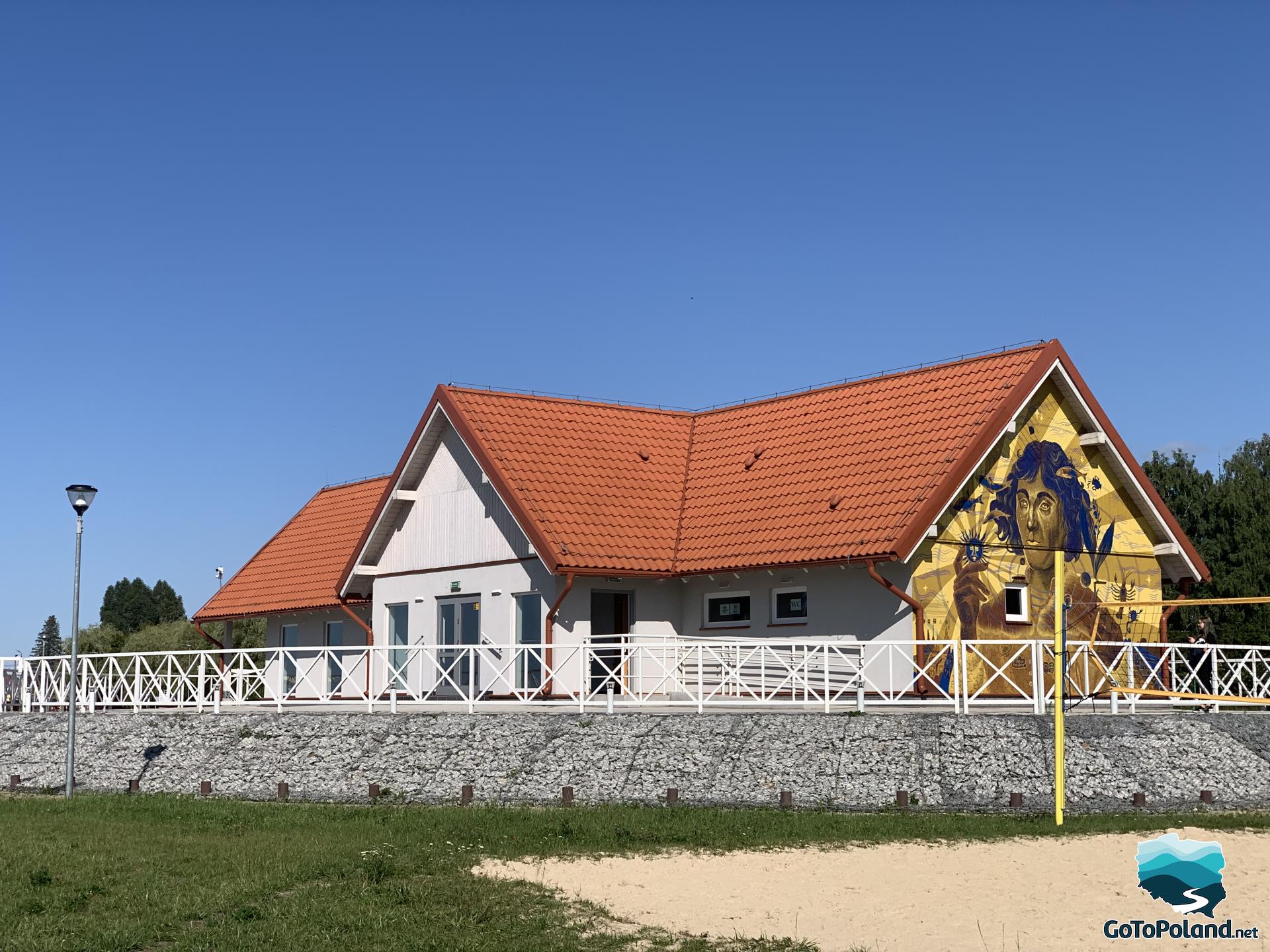 a white building with red roof and a mural of Copernicus