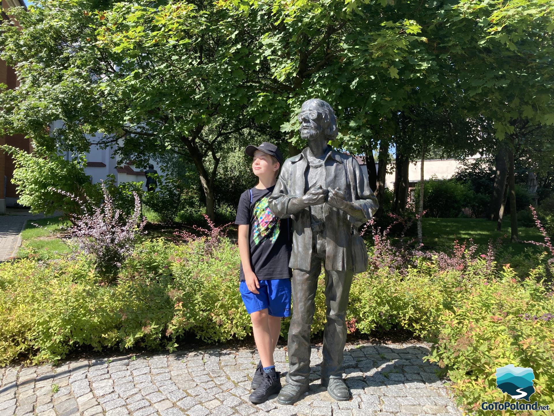 a boy standing next to the figure 