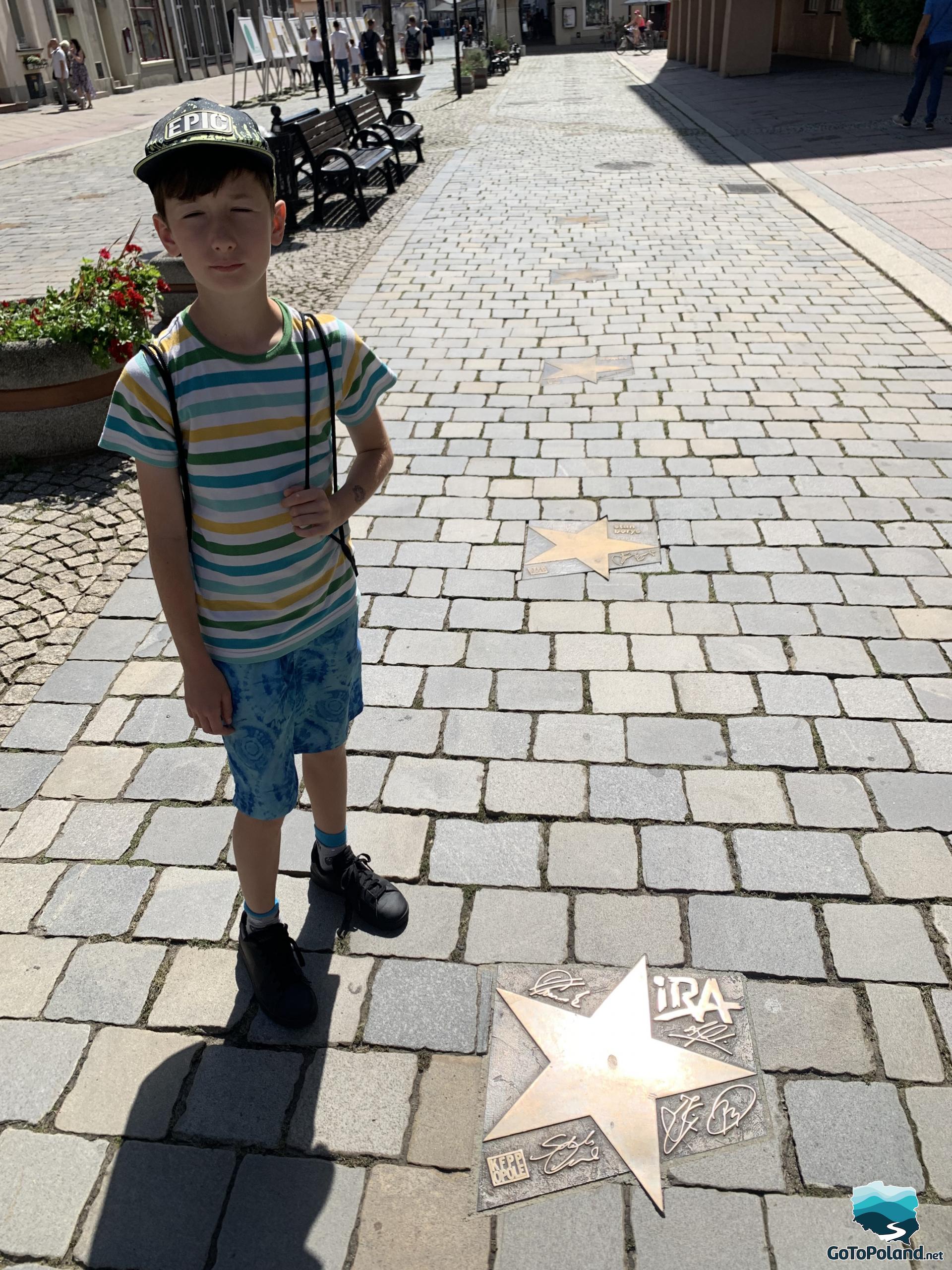 a boy standing on the famous Avenue of Stars, in the walk there are stars assigned to individual artists