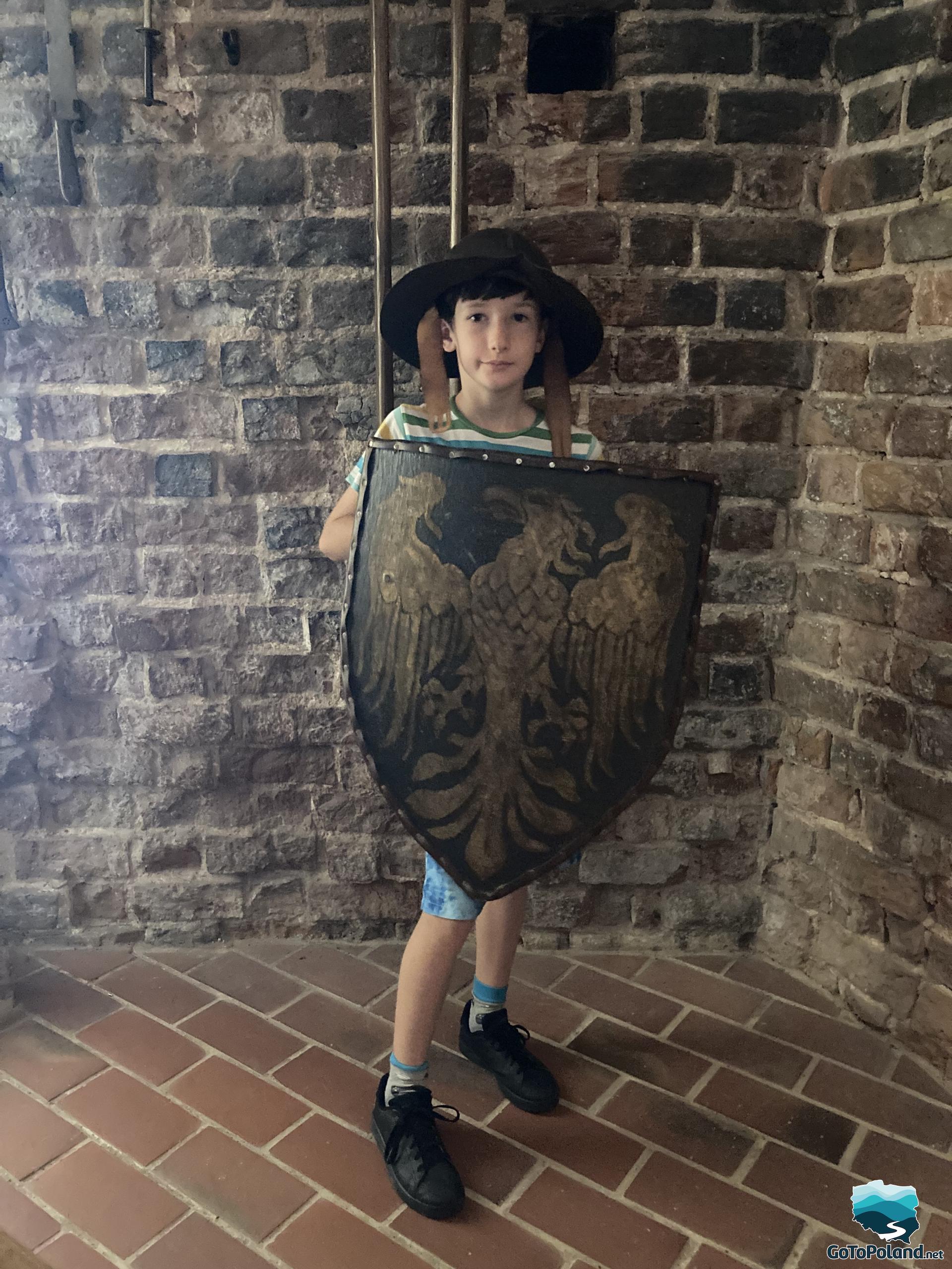 a boy standing in a tower, with a helmet on his head and a shield in his hand