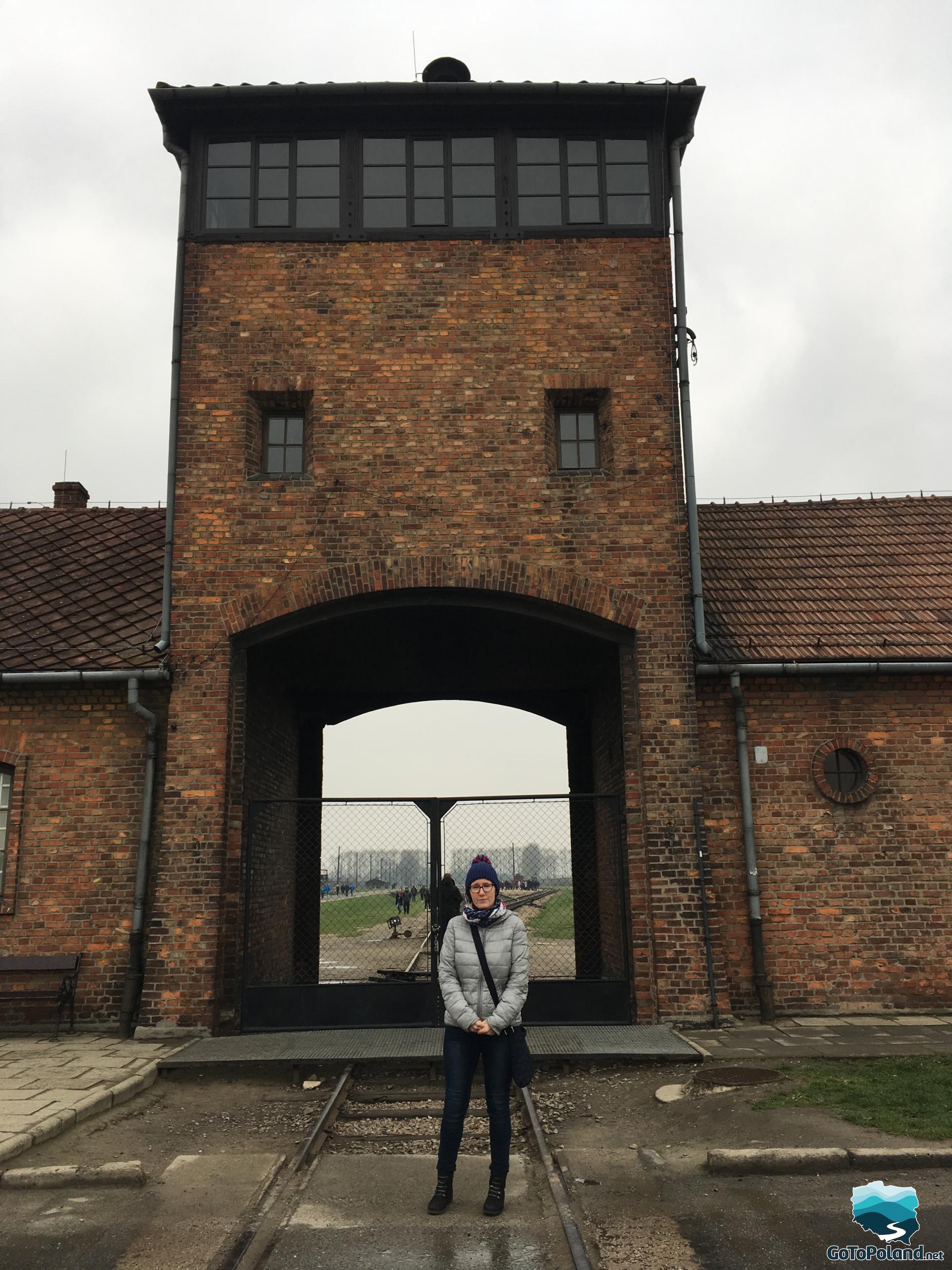 woman standing in front of the entrance gate to Birkenau