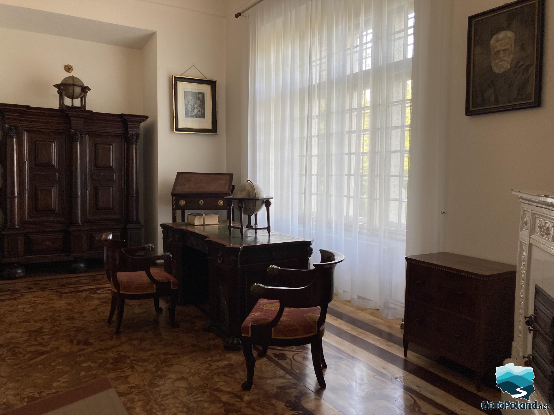 Room with wooden furniture, large oak desk, two chairs, and a wardrobe