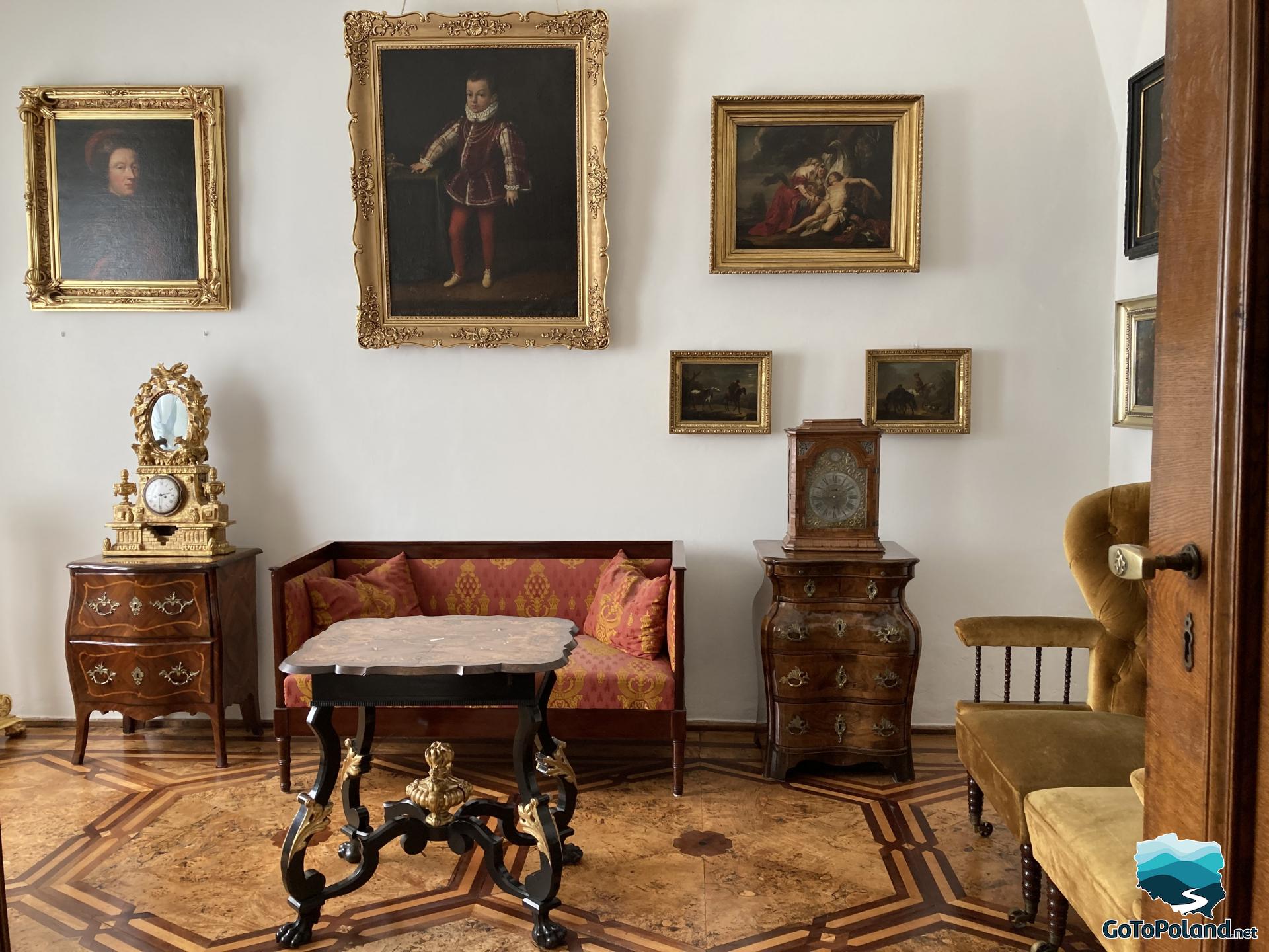 five paintings hanging on the wall, carved table, inlaid floor, two antique clocks 