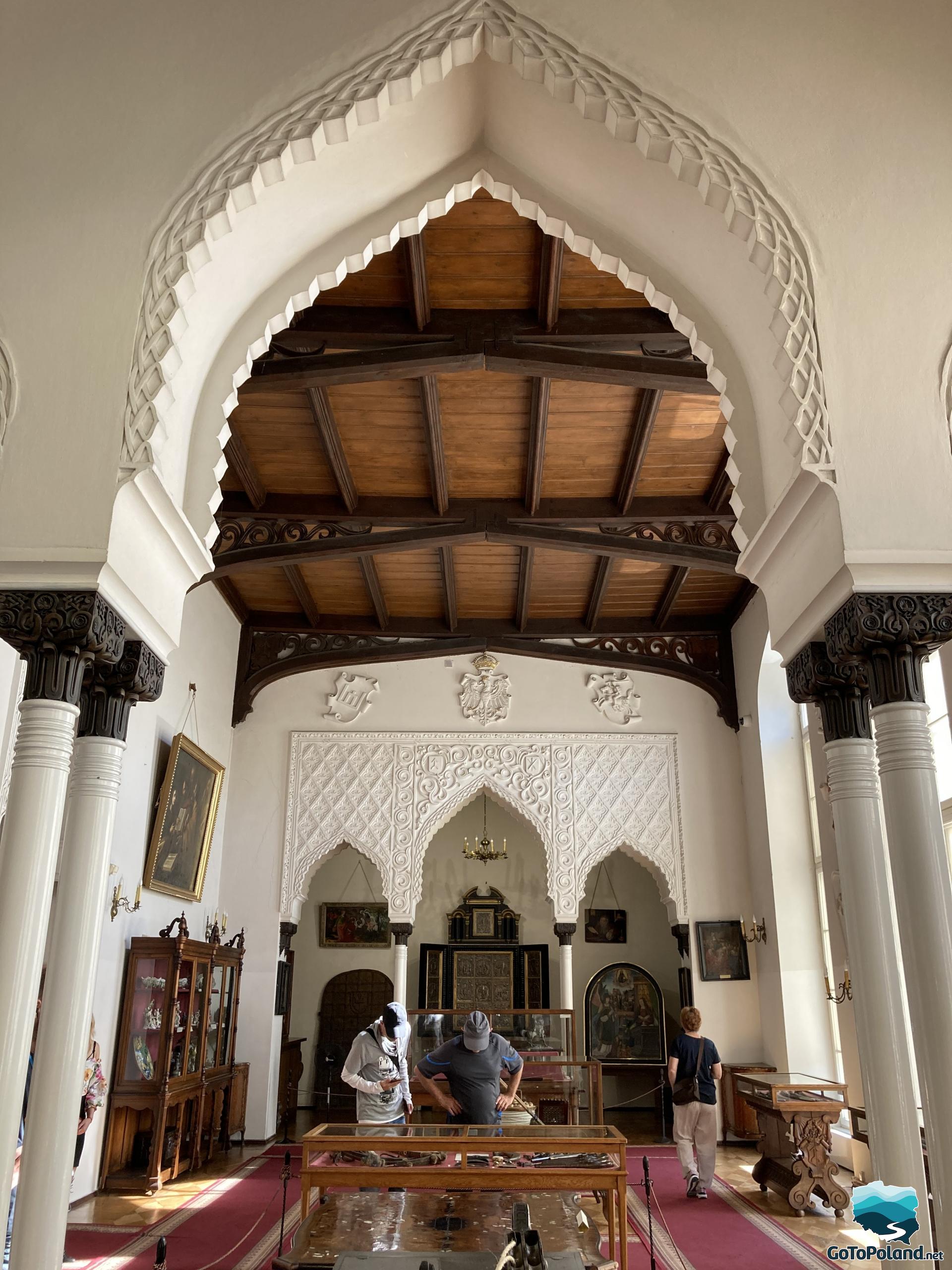 a room in the Moorish style, shelves with porcelain, three tourists viewing the exhibitions