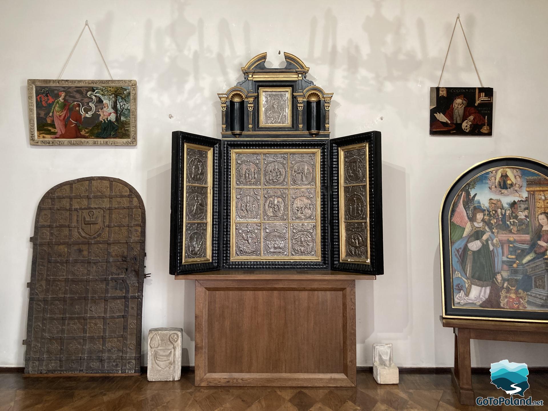 silver altar in the form of a triptych surrounded by a few paintings