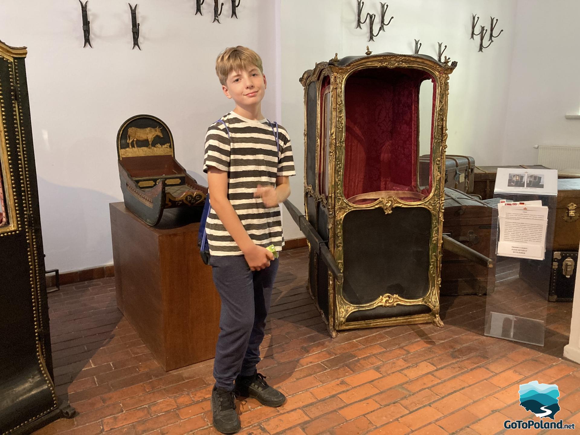 a boy is standing next to a sedan chair