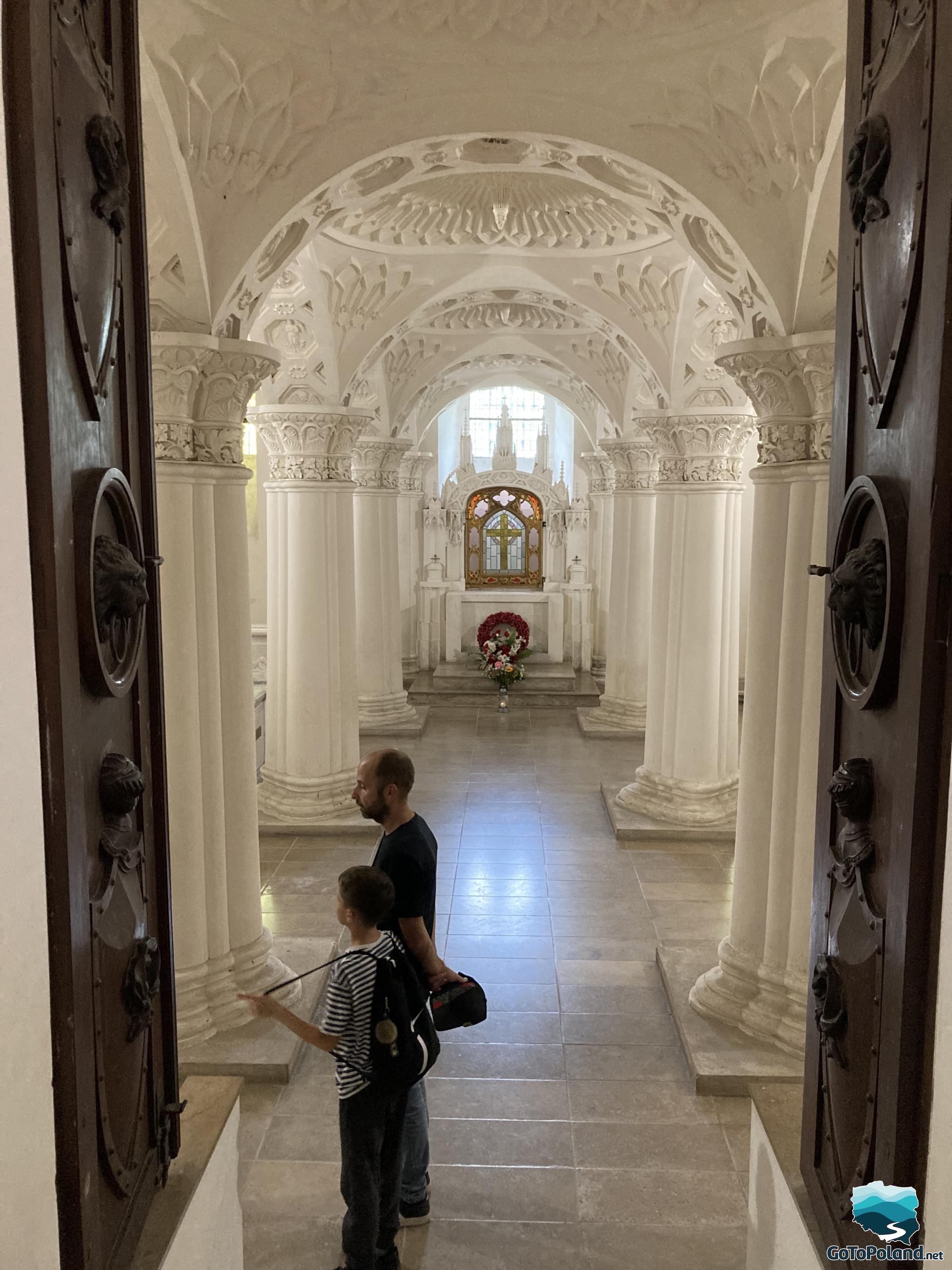 a boy and a man are in a mausoleum with white columns 