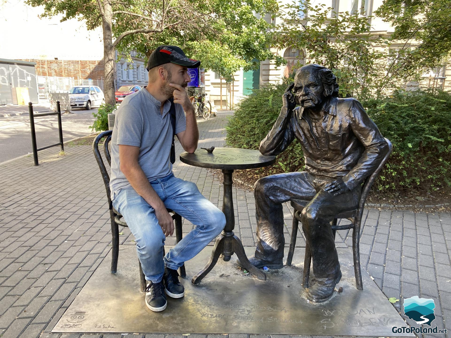 a man sits next to a sculpture of a man
