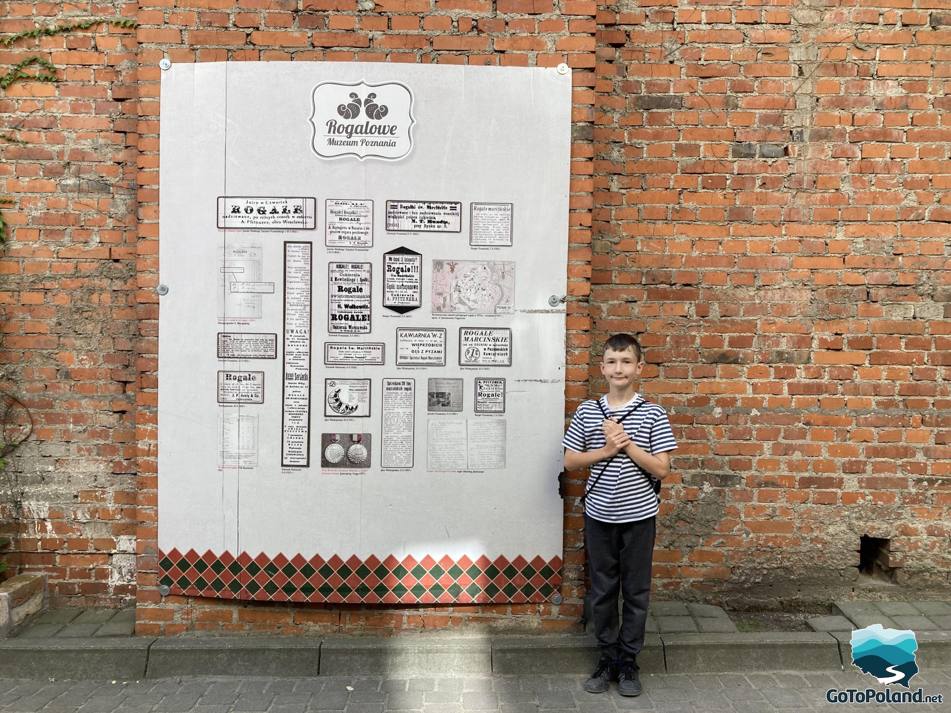 a boy standing in front of a large sign advertising the Croissant Museum