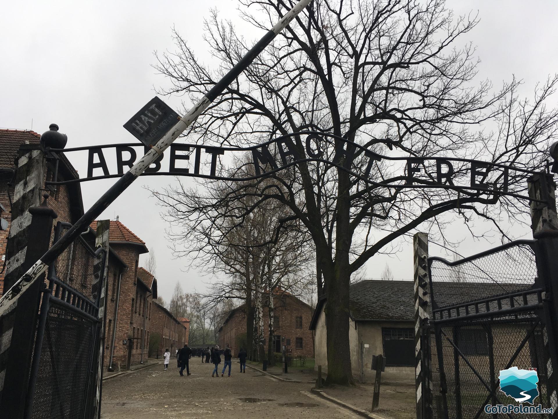 the main entrance to former camp with gate and an inscription Arbeit macht frei