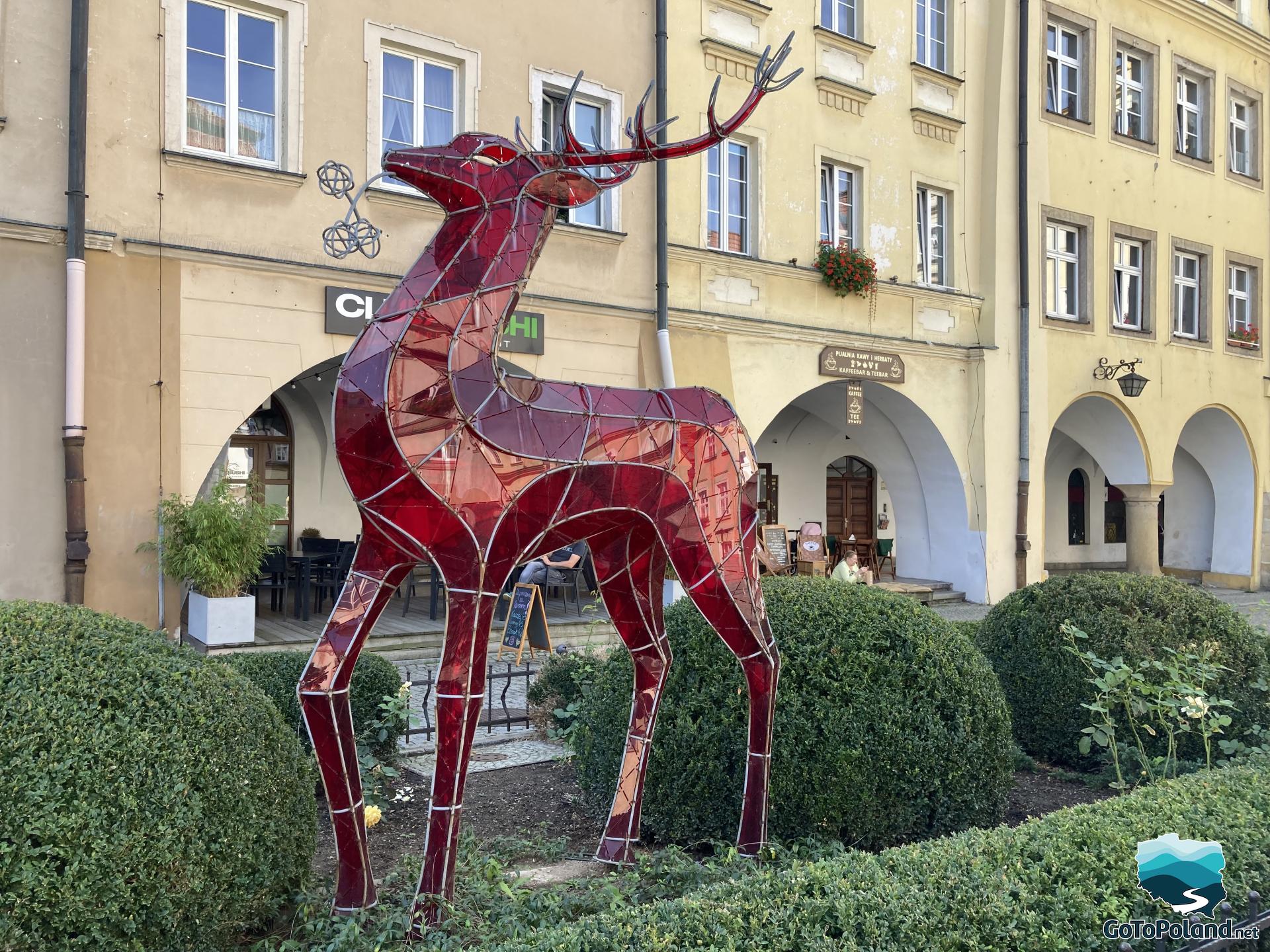 red artificial deer made of glass standing in the square