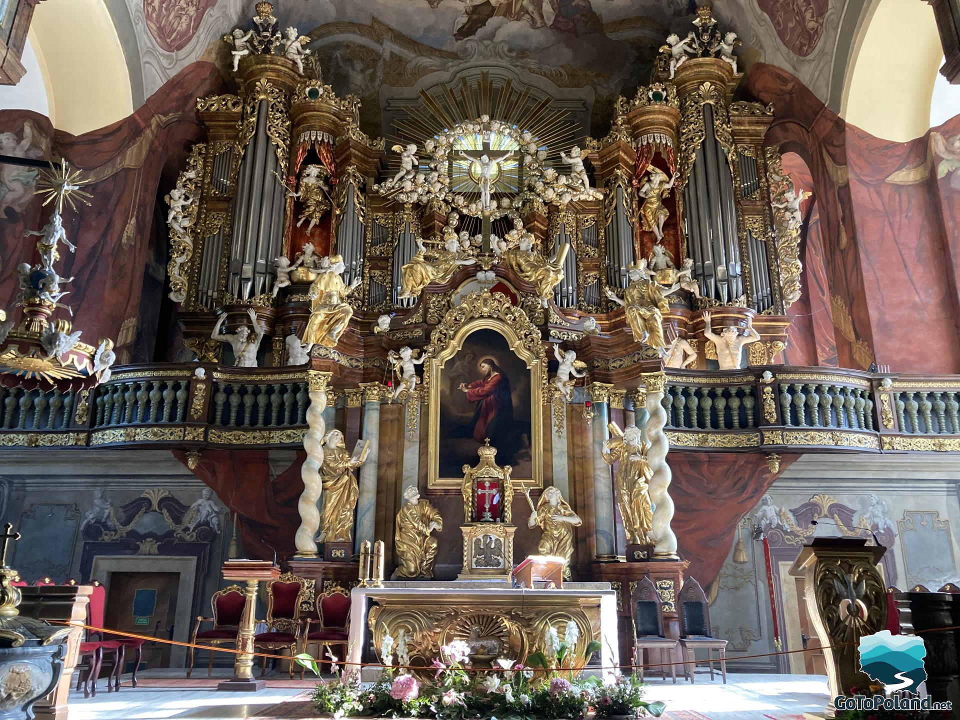 the main altar with sculptures and a painting of Christ, and an organ above the altar