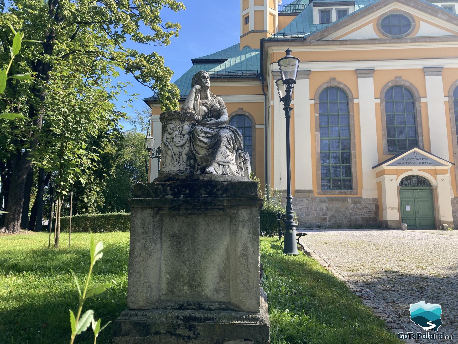 a stone sculpture on the pedestal in front of a church