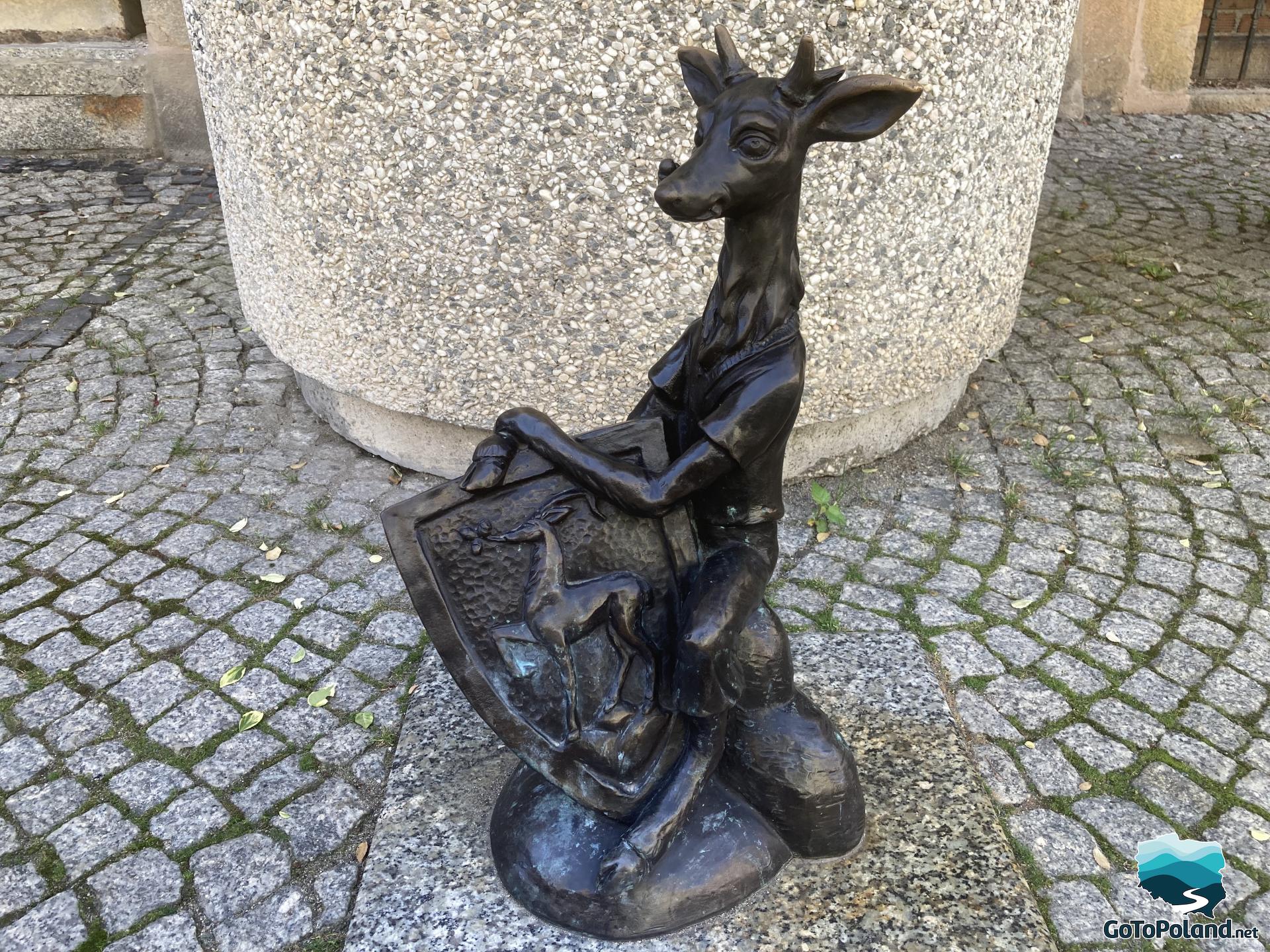 a small statue of deer with a coat of arms