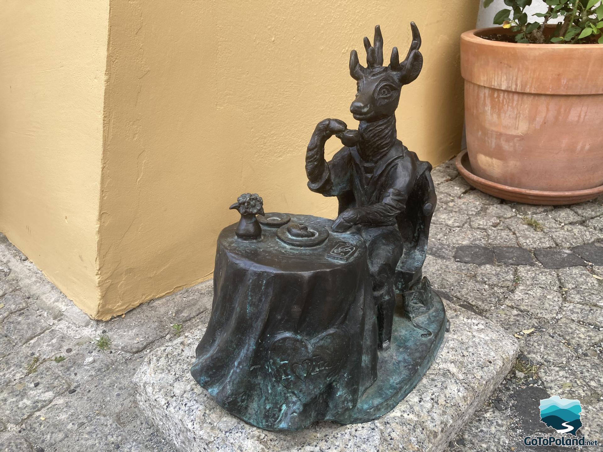 a small statue of deer sitting by the table with a cup of coffee