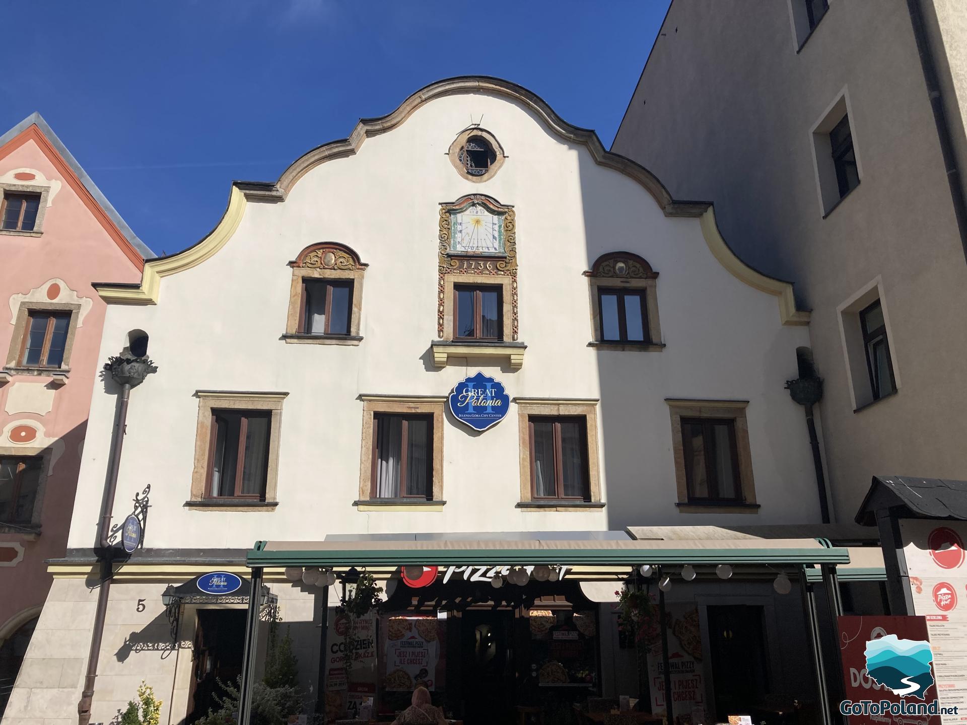 tenement house with a clock and a restaurant on the ground floor