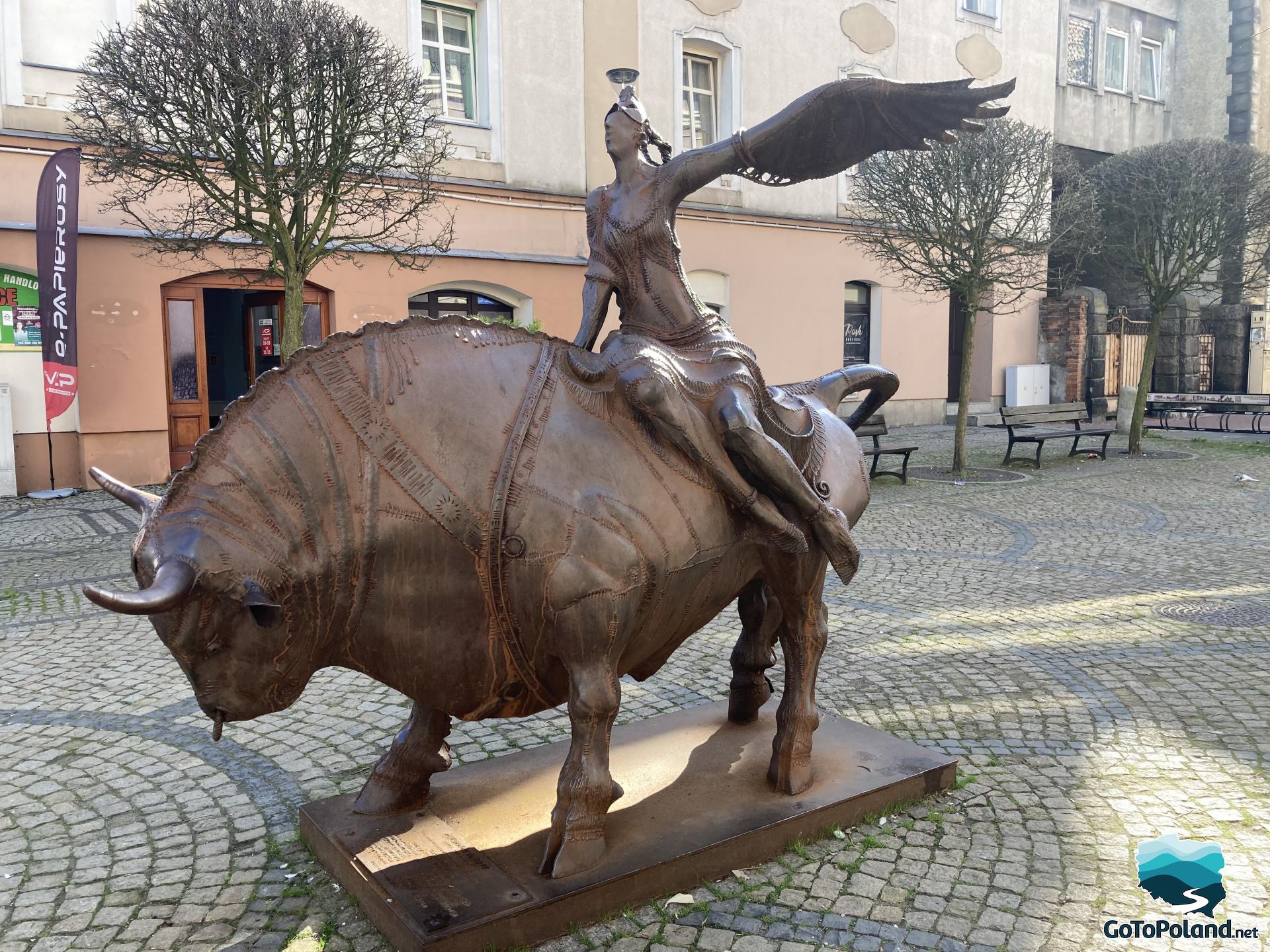 a bronze metal sculpture depicting a bull and a woman sitting on it,