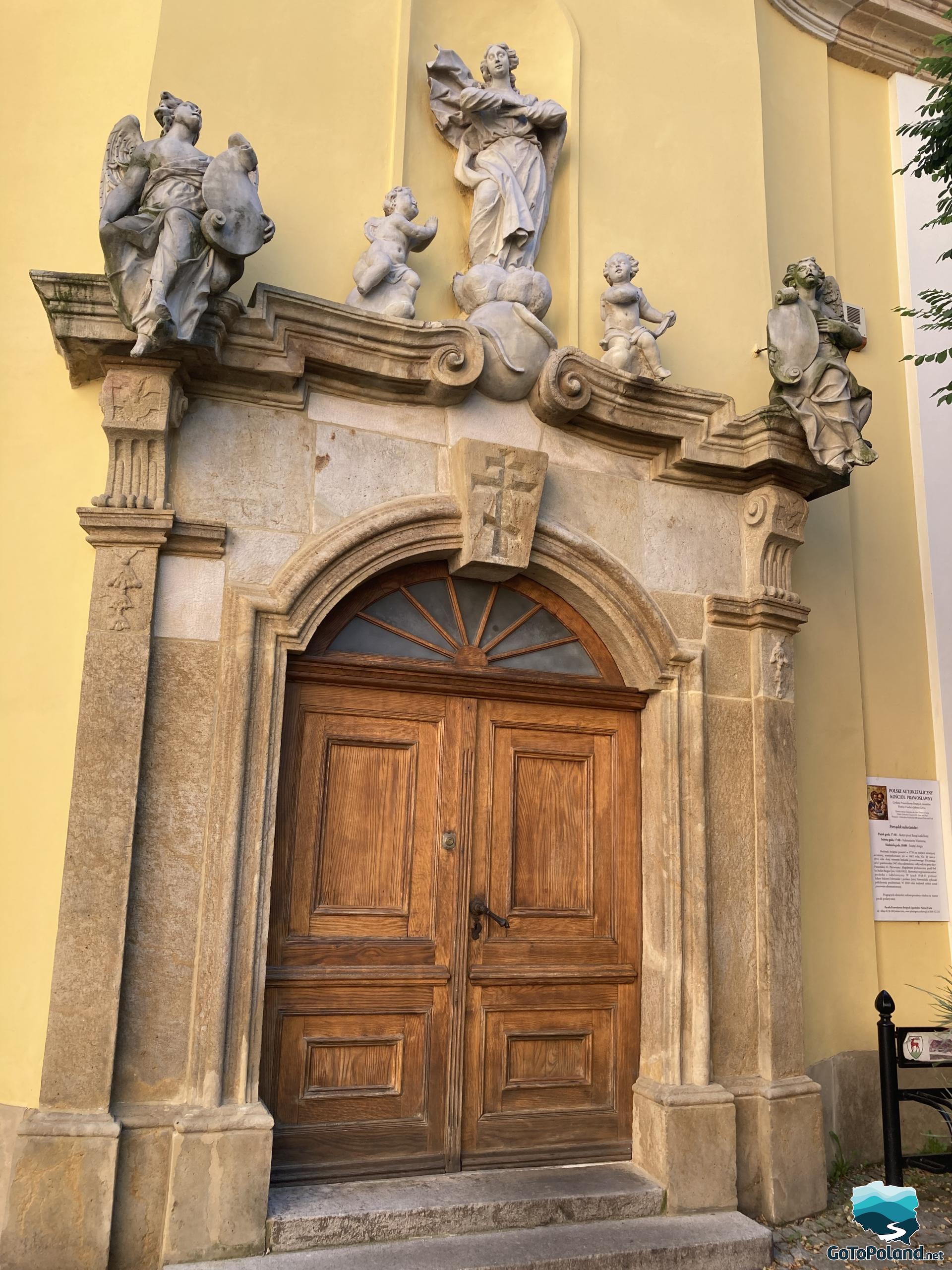 doors leading to the church with statues of saints above them