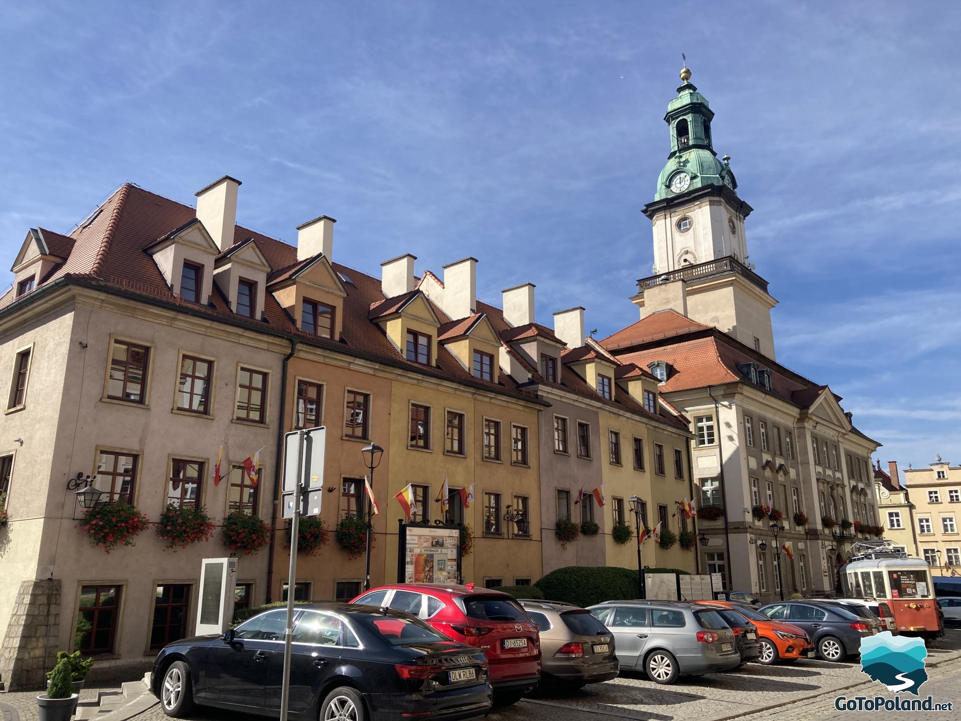 a row of tenement houses connected to the town hall. Cars are parked in front of them