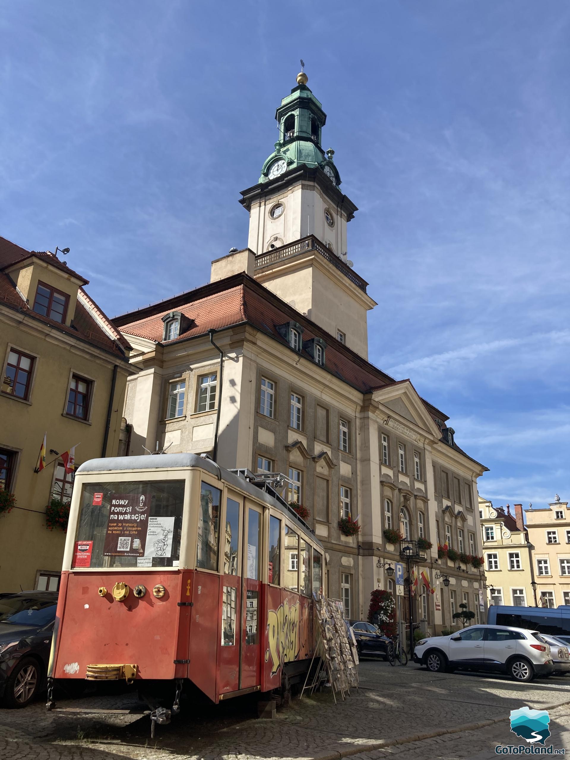 a red tram serving as a shop and a town hall behind it