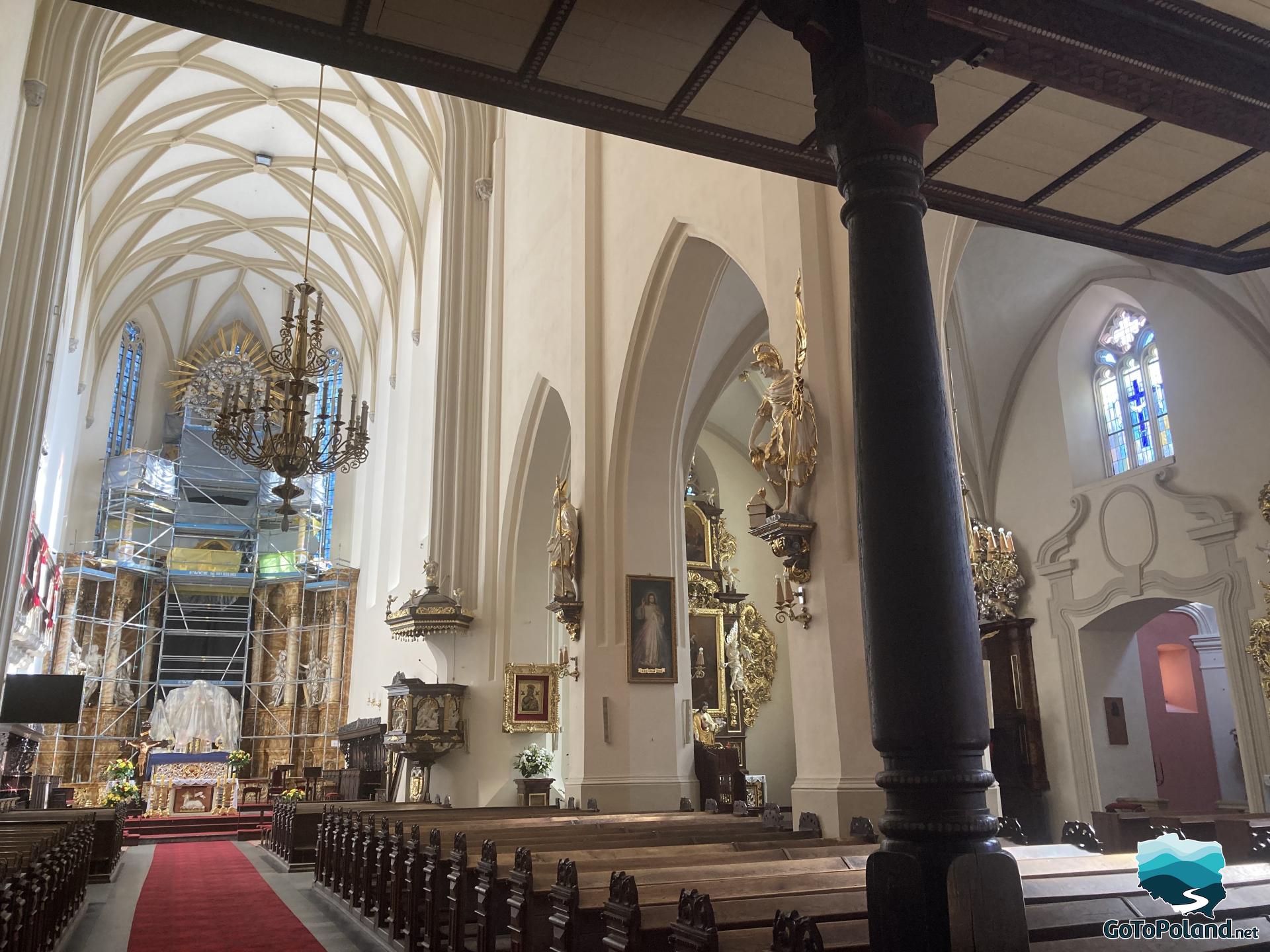 a row of benches in the basilica, an altar and two chandeliers