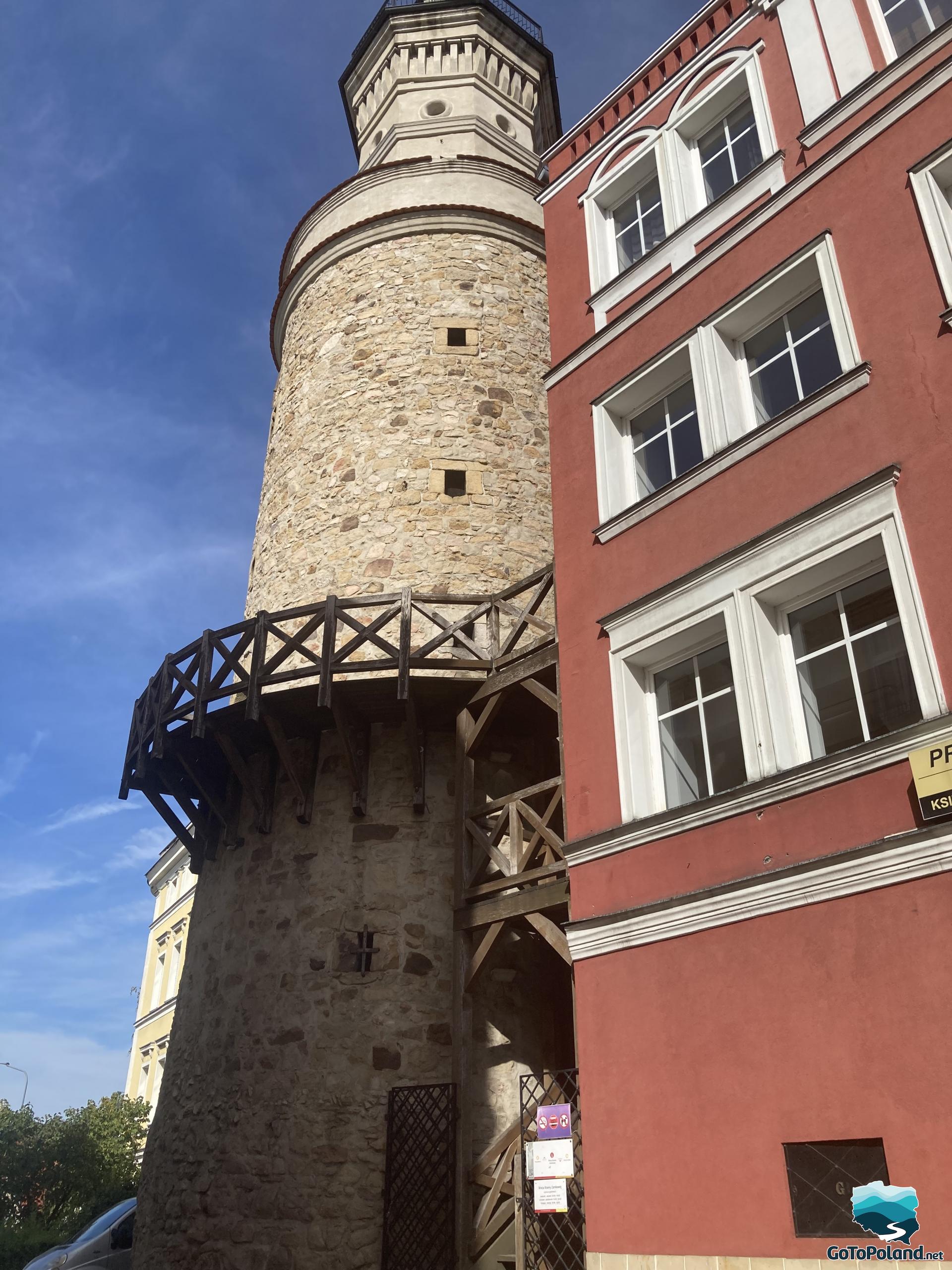 a stone tower with a wooden viewing terrace, attached to the tenement house