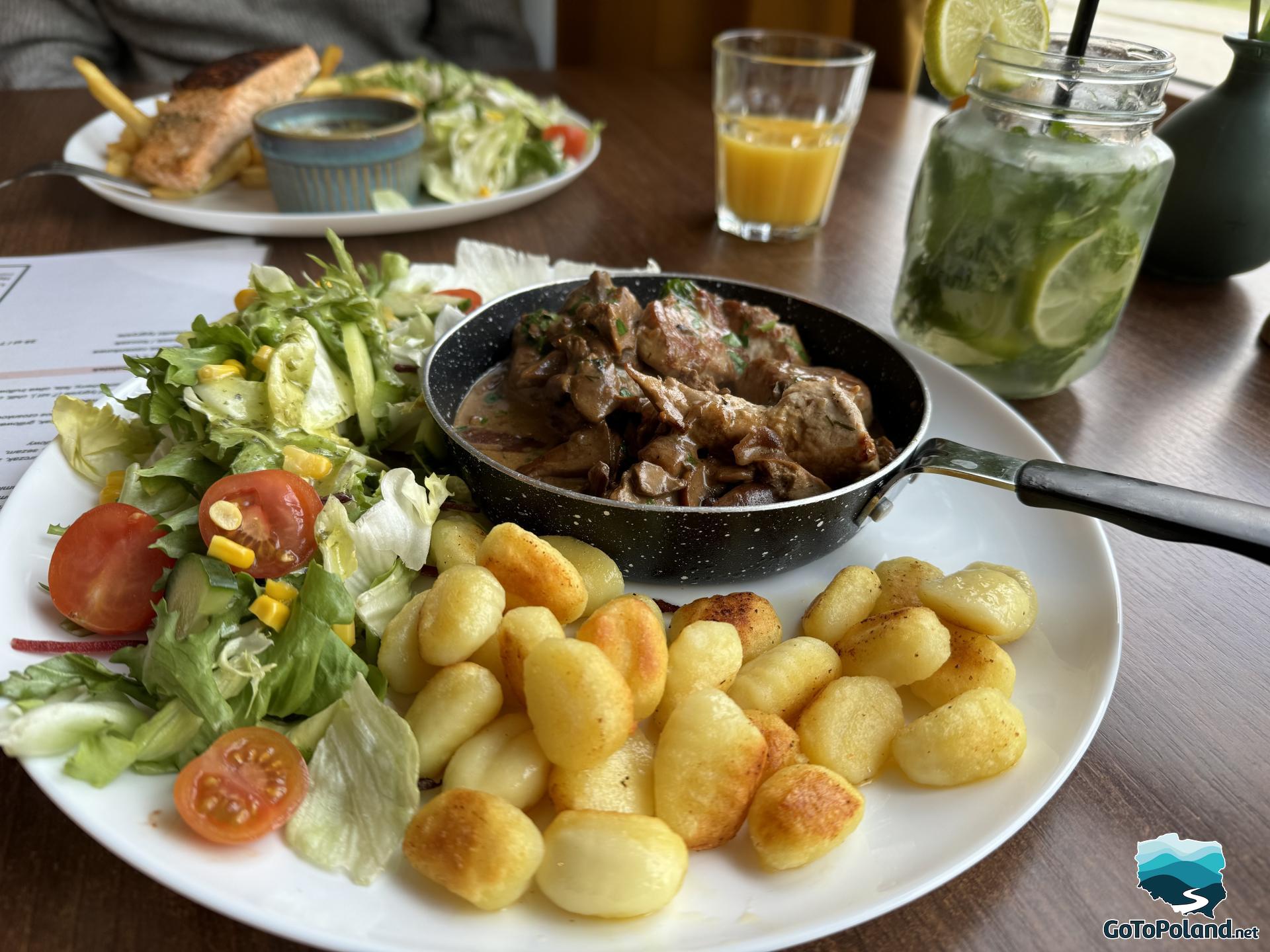 a plate with small dumplings, meat stew and salad