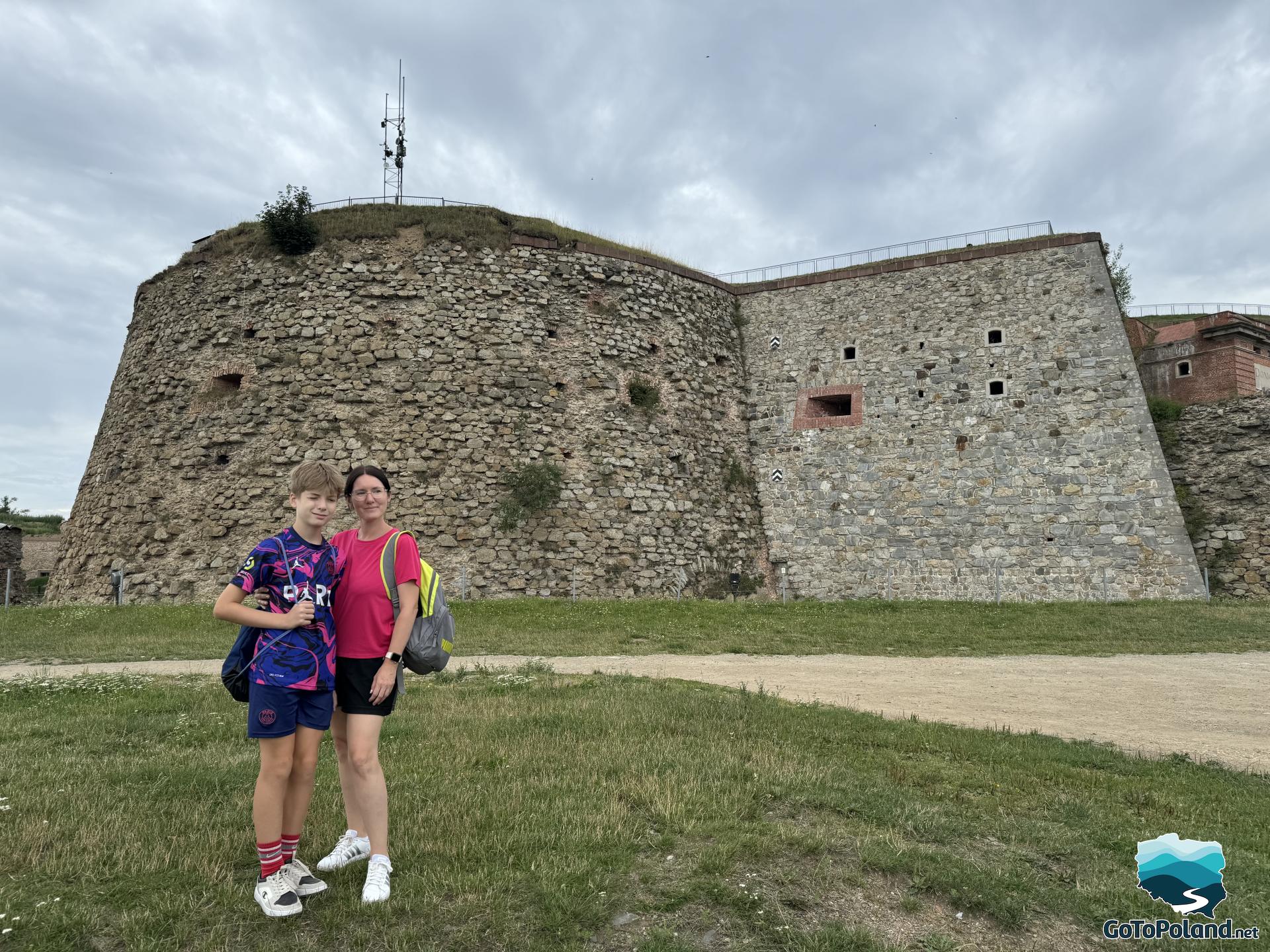 a woman and a boy are posing in front of a fortress