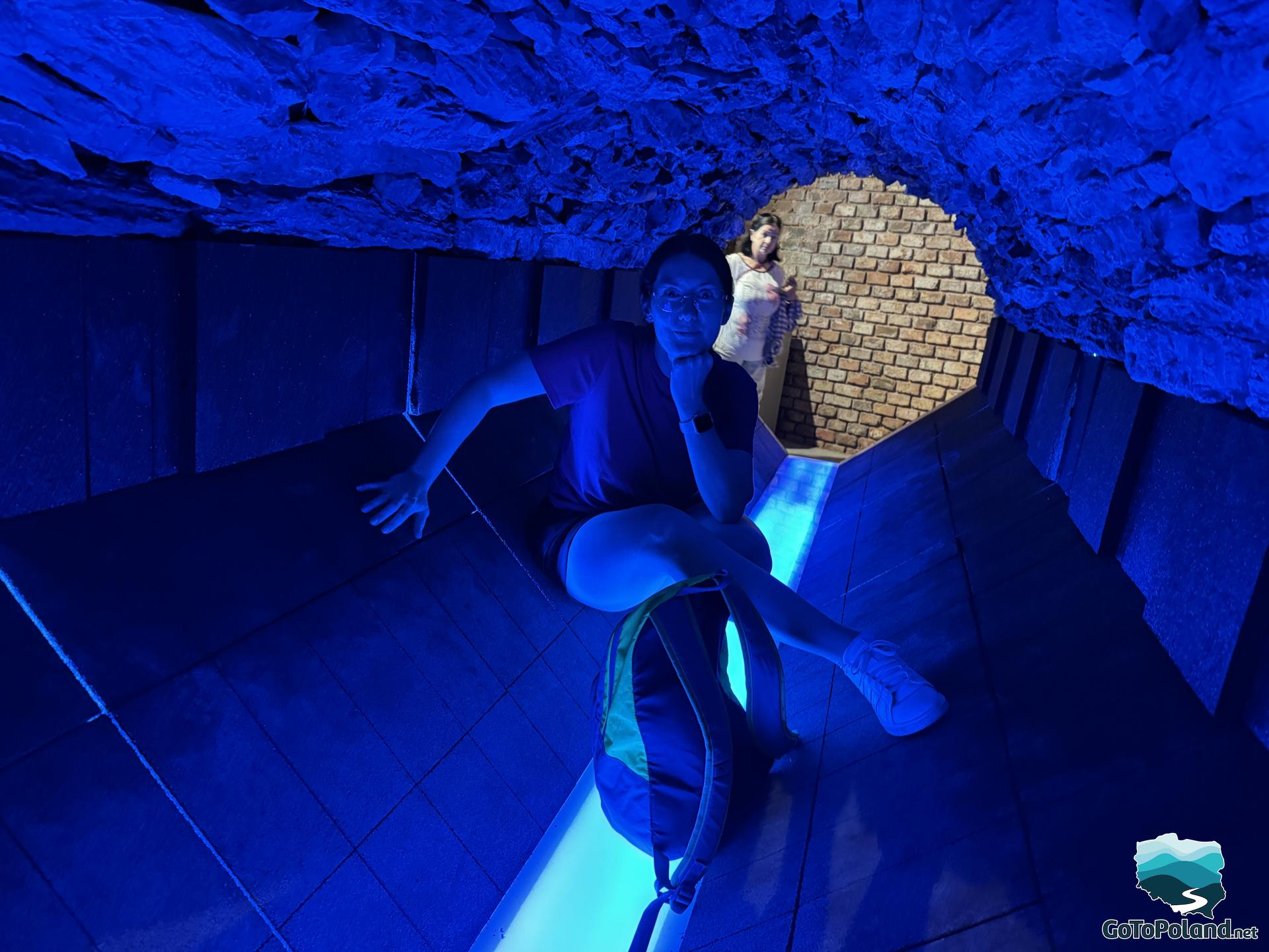 a woman sits in a blue tunnel