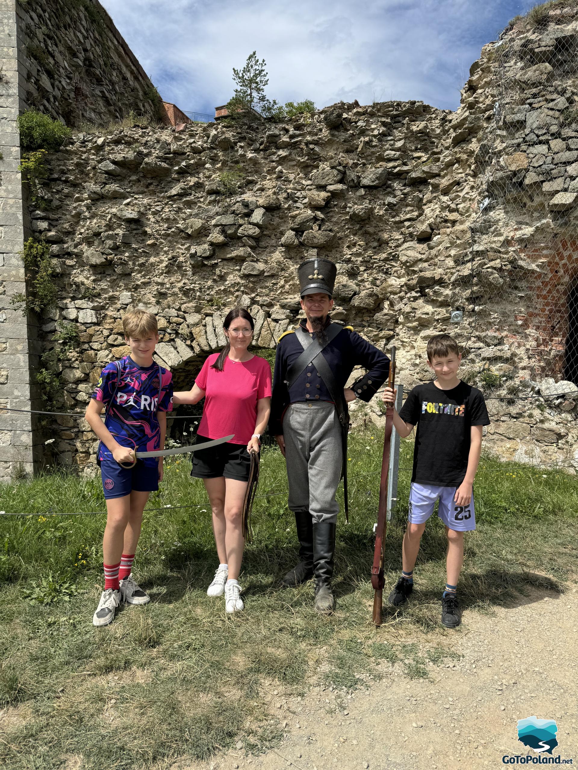 Two children and a woman pose with a man dressed as a Prussian soldier