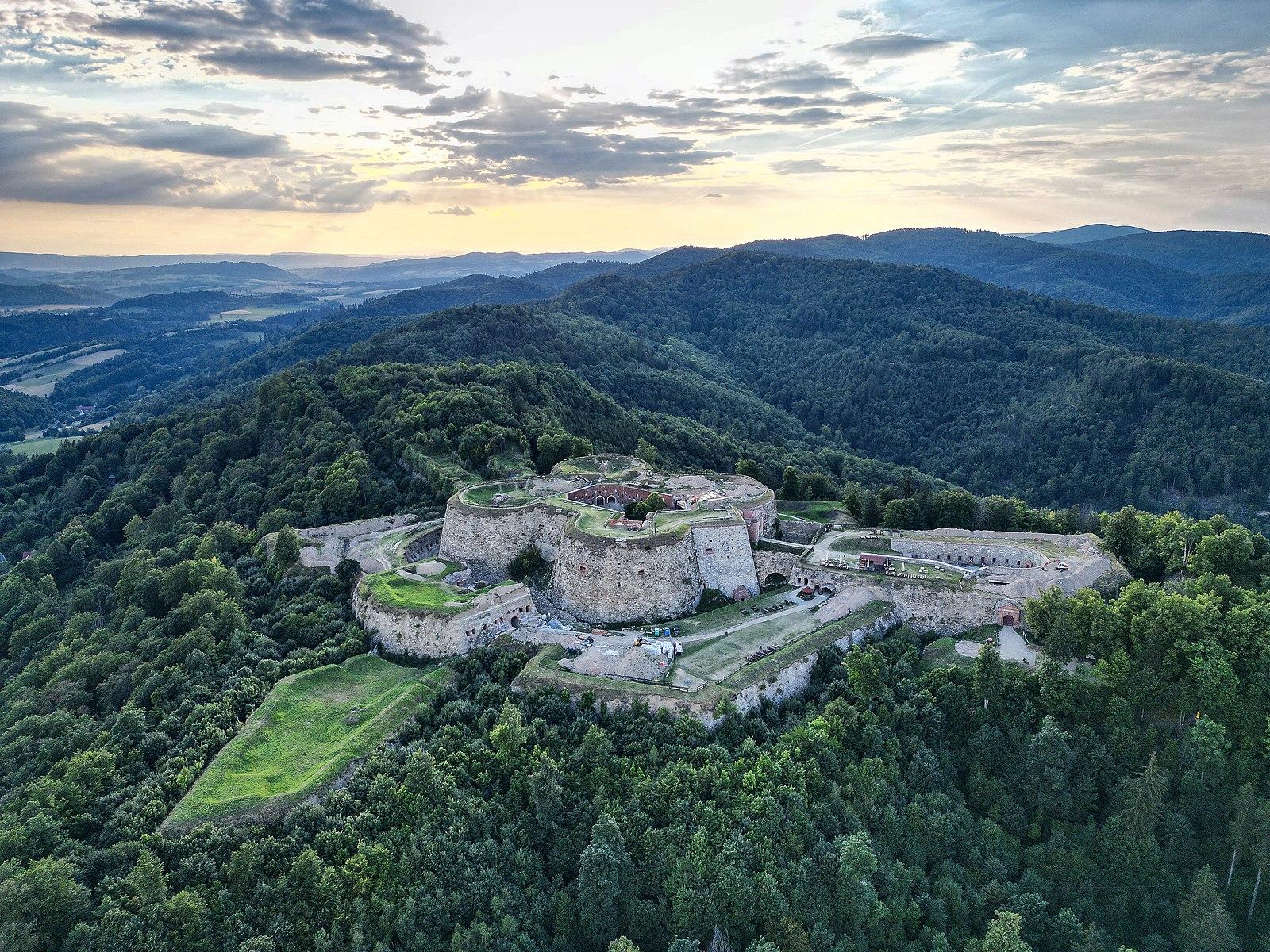 a big fortress surrounded by green hills 