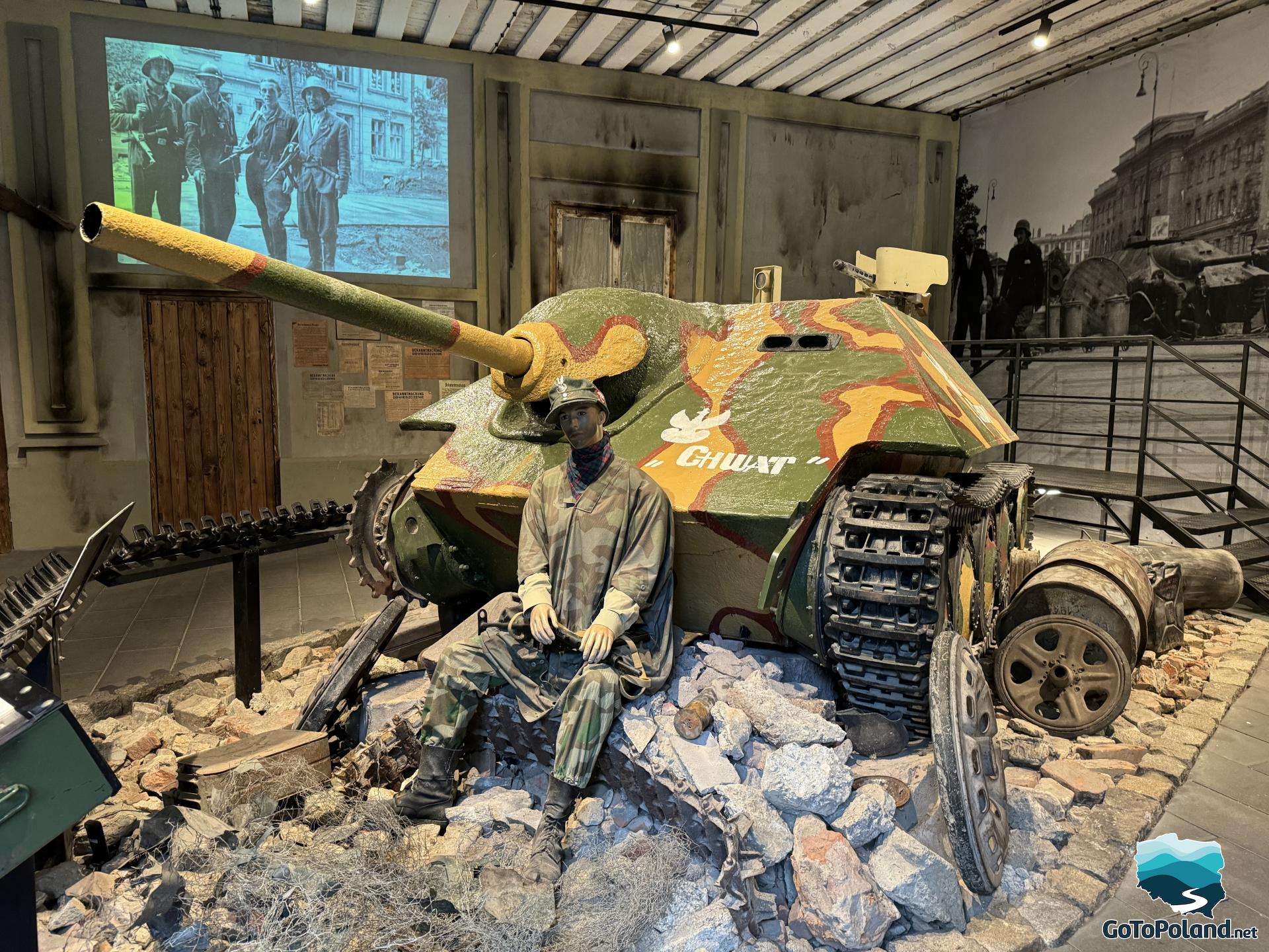 a tank with a mannequin sitting next to it, representing an insurgent