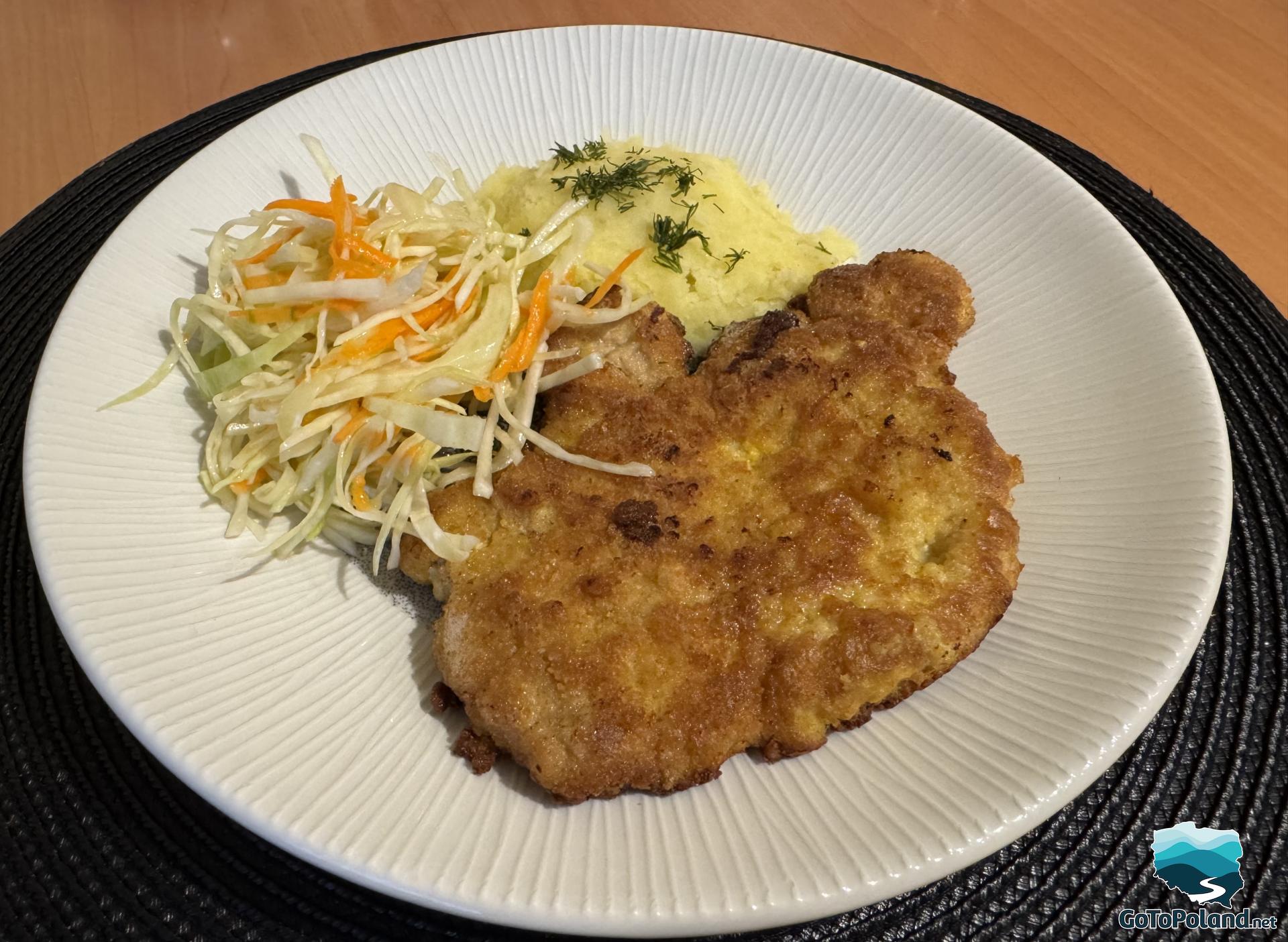 a pork chop with salad and potato on a white plate  