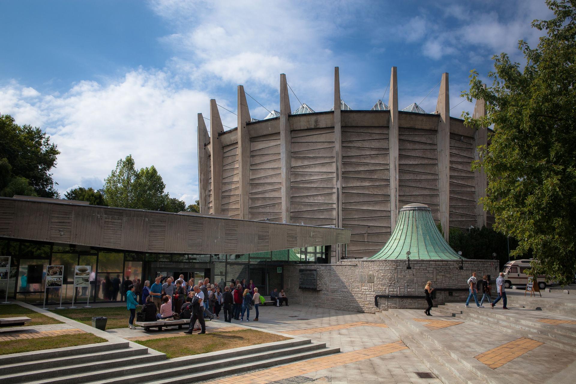 a group of tourists waiting to enter the round building