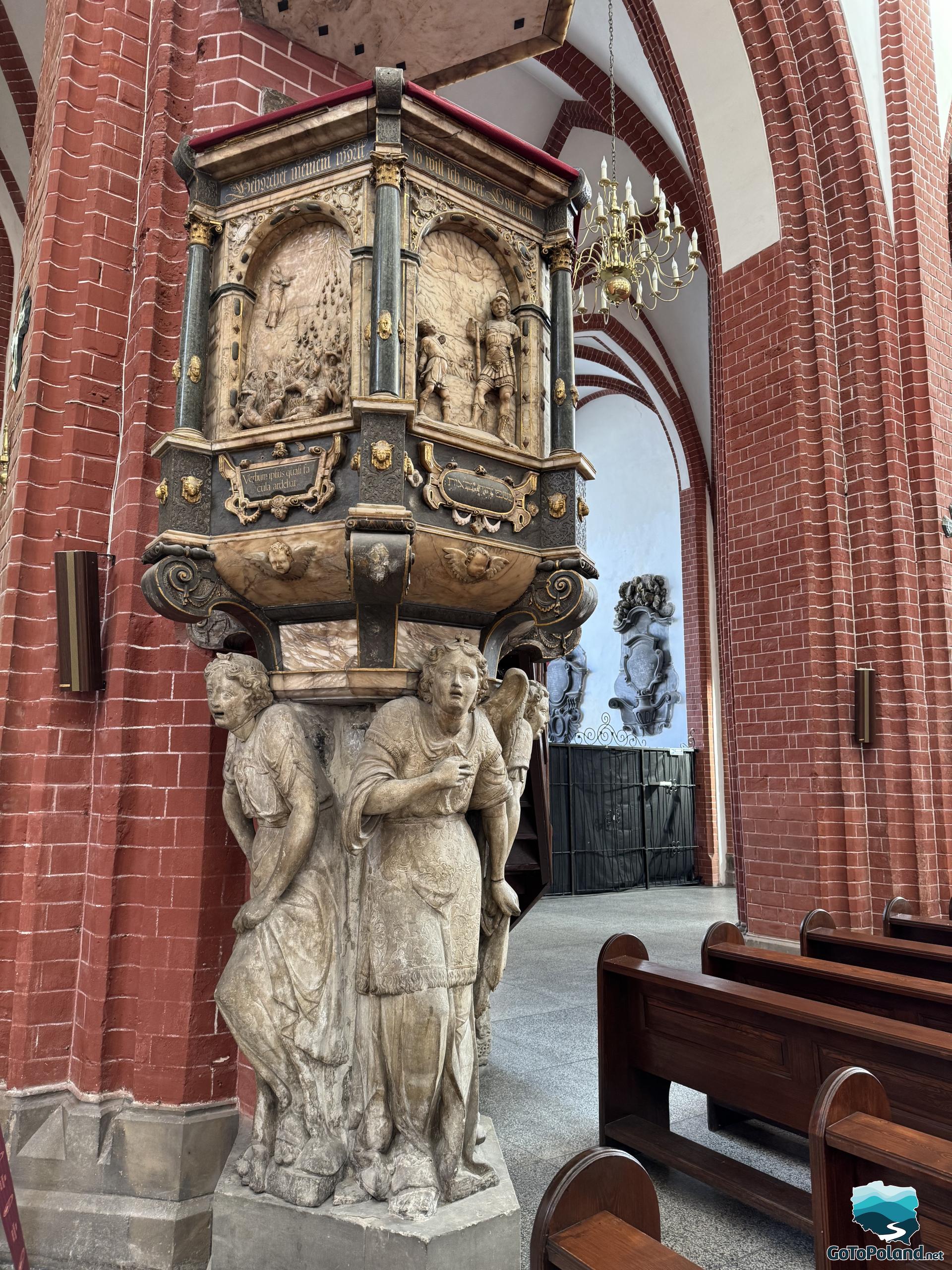 old pulpit in a church which is hold by the stone figures