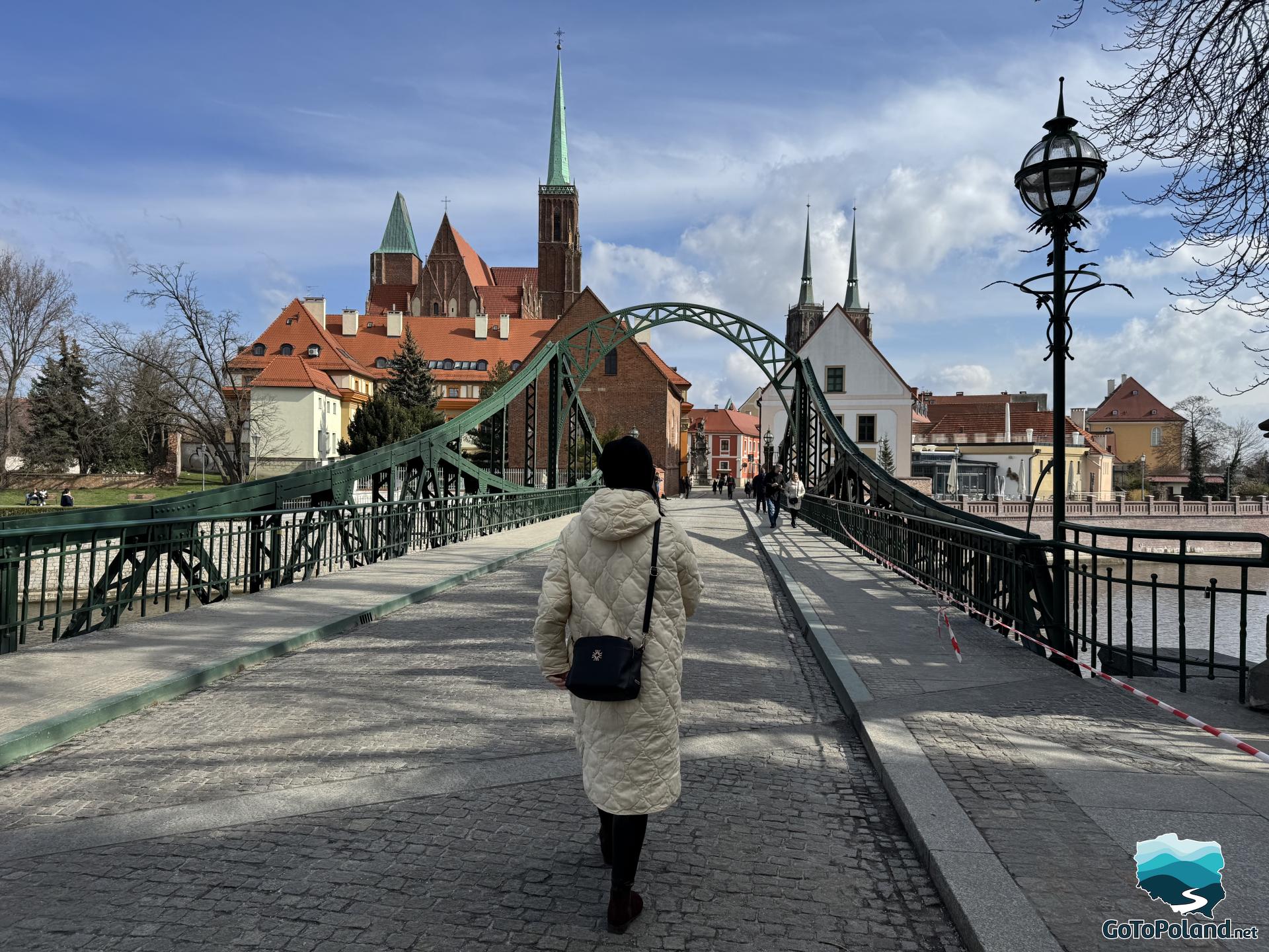 a woman steps onto a cobblestone bridge that leads to the old part of the city