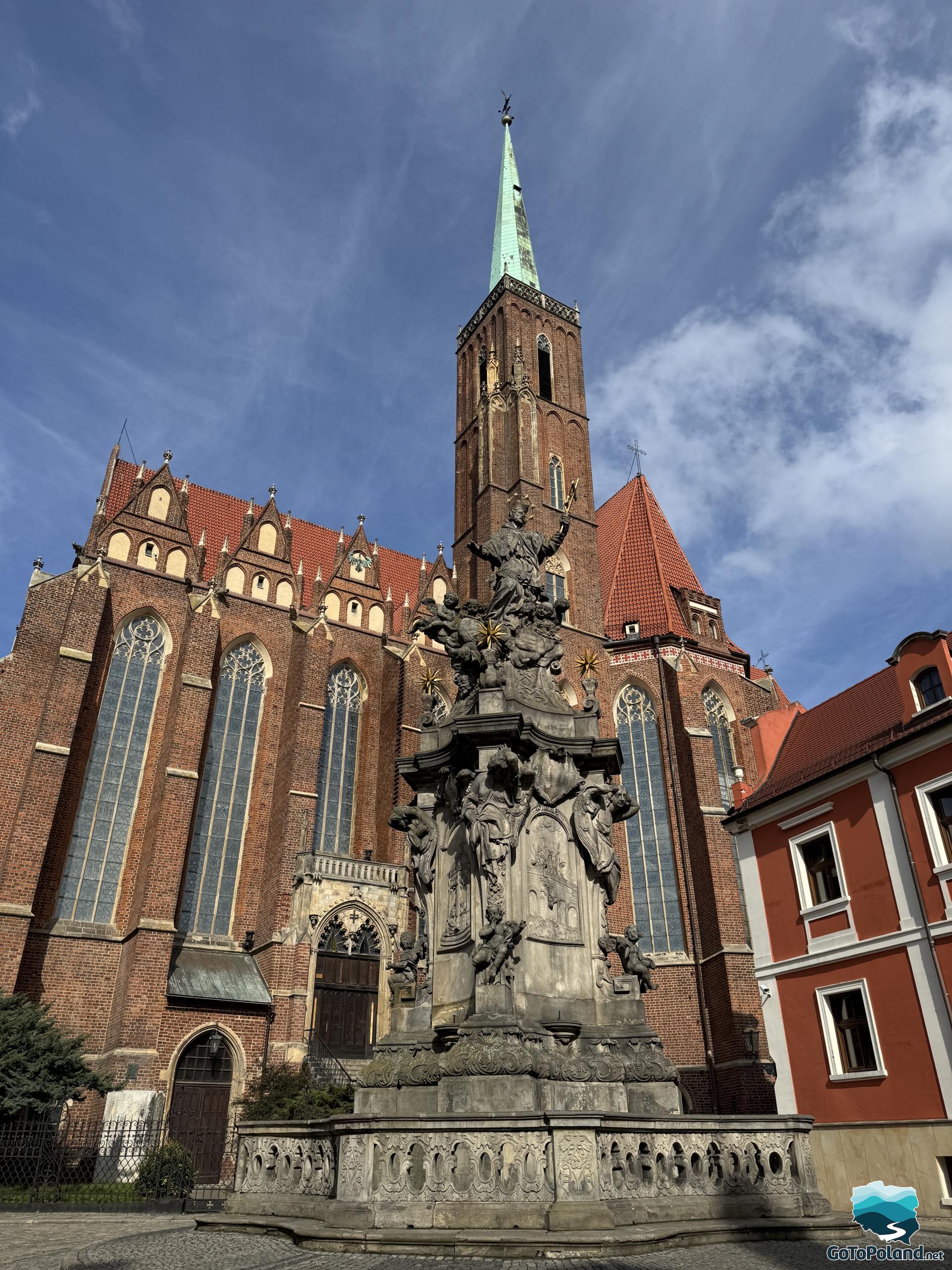 stone statue behind it church with 1 high tower