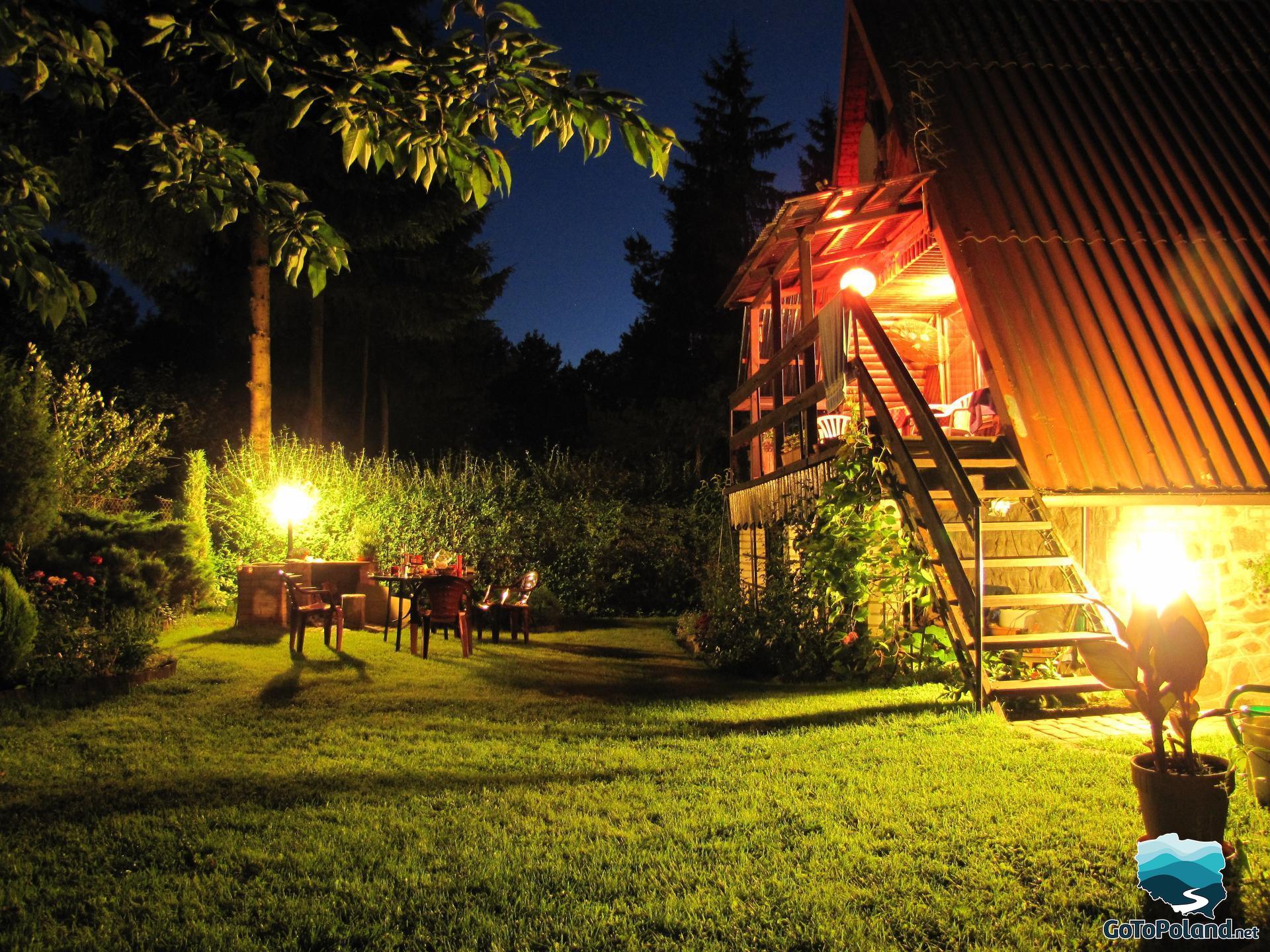 A summer house at night illuminated by several portable lamps