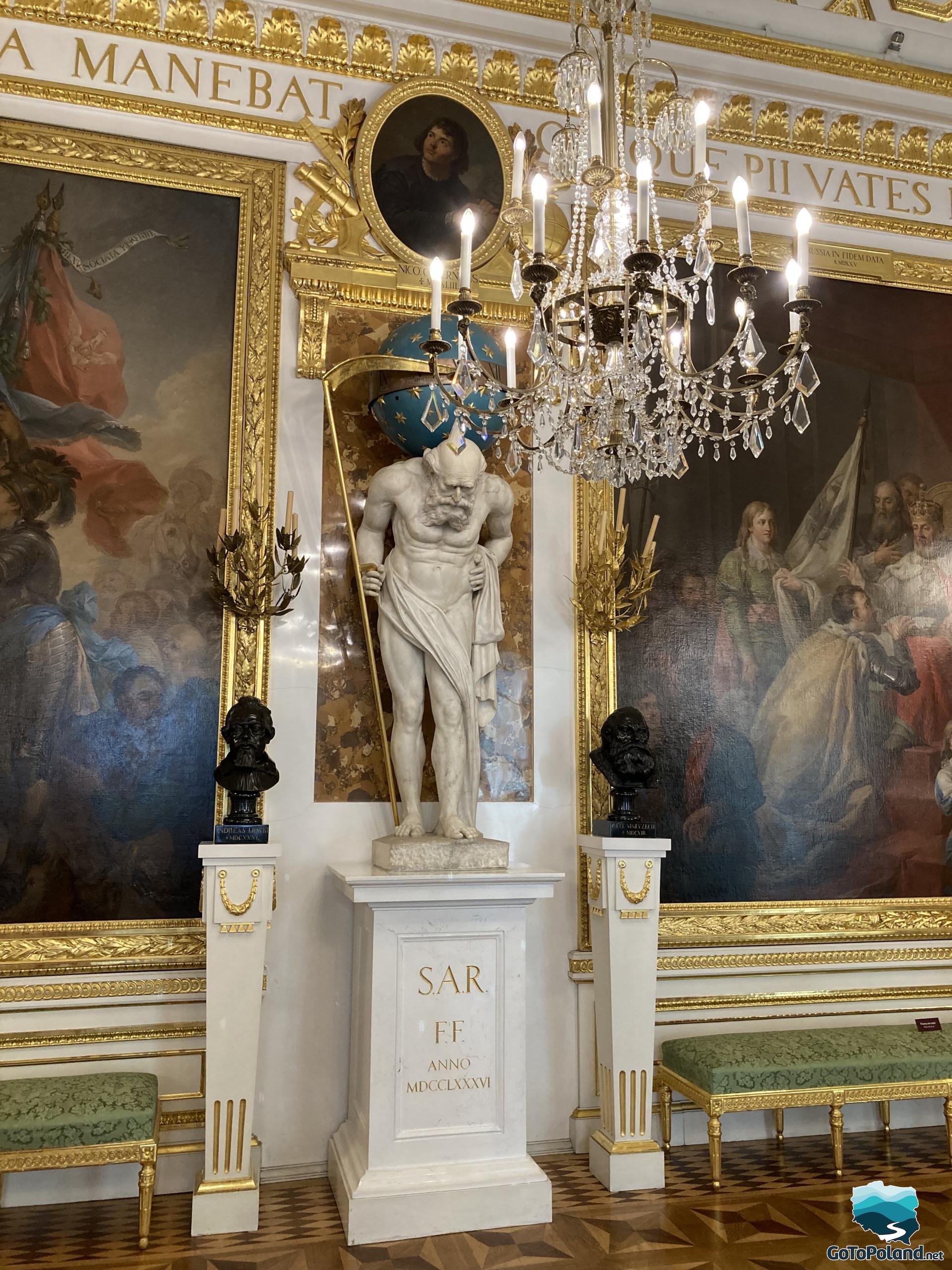 sculpture of a man in the Roman style who carries a huge blue ball on his shoulders, on both sides, next to him are two pedestals with male busts and two large paintings in golden frames
