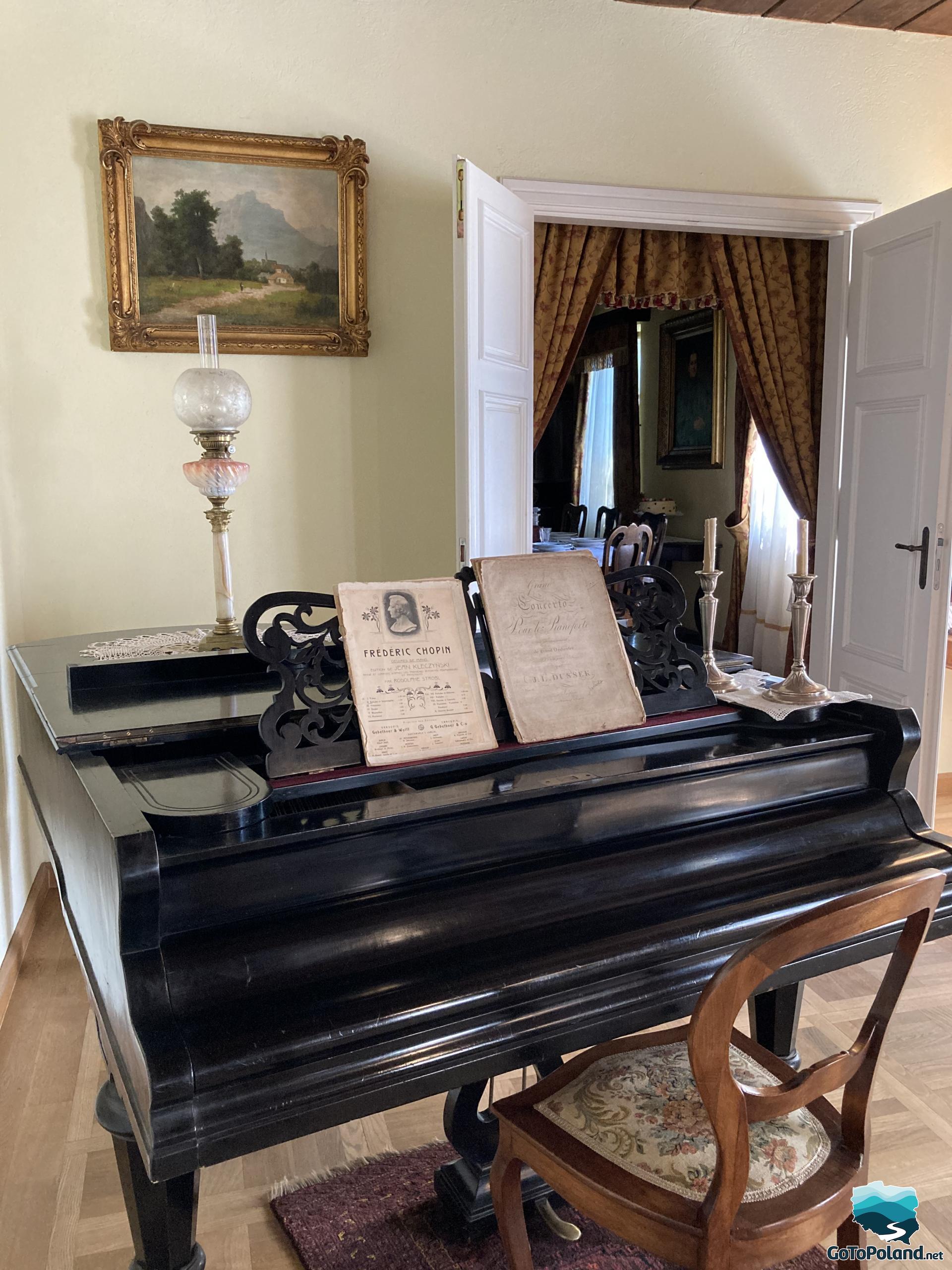 a black piano stands inside the manor, on the piano there is a Chopins piece