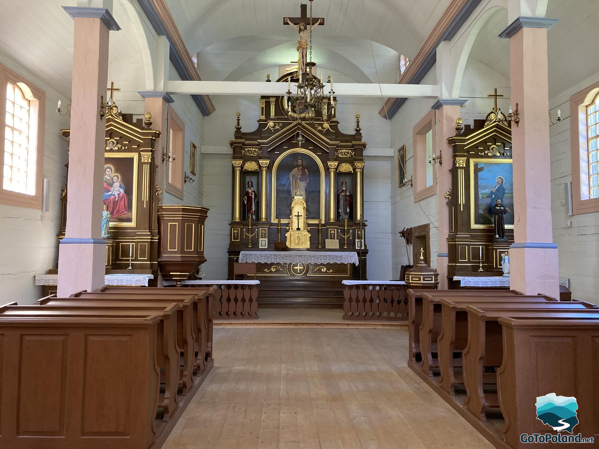 an interior of the church, main altar in the background, wooden benches